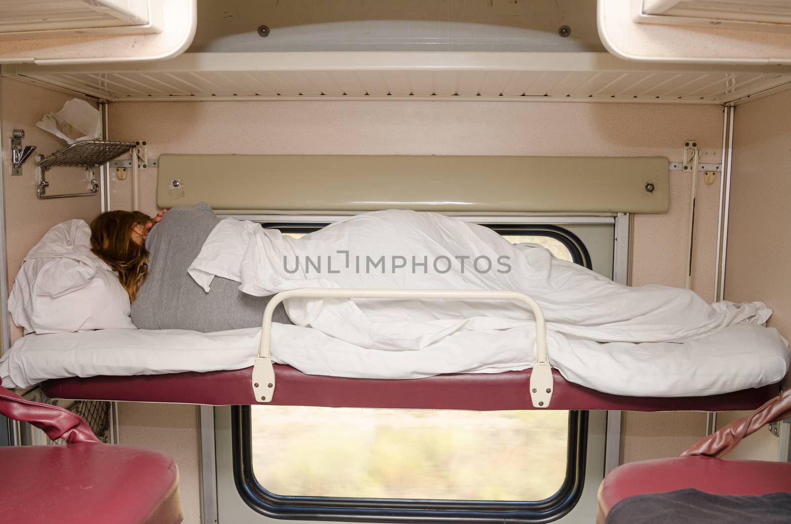 Passenger train sleeping on the top shelf of the side seats in the second-class carriage turned to the wall