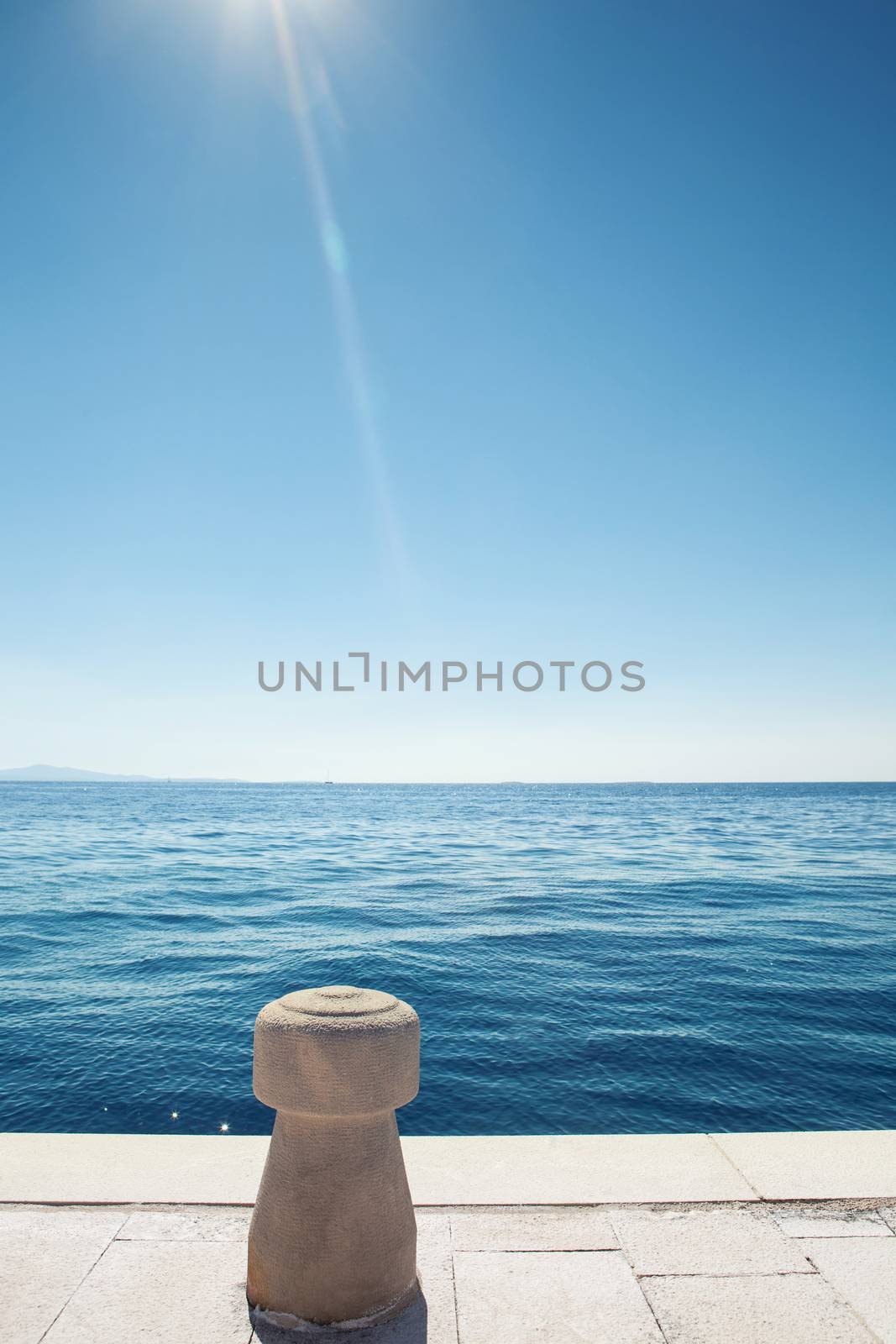 stone bollard on boat dock and blue sea