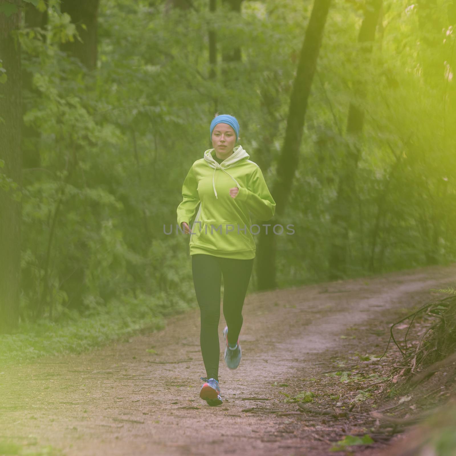 Sporty young female runner in the forest.  by kasto