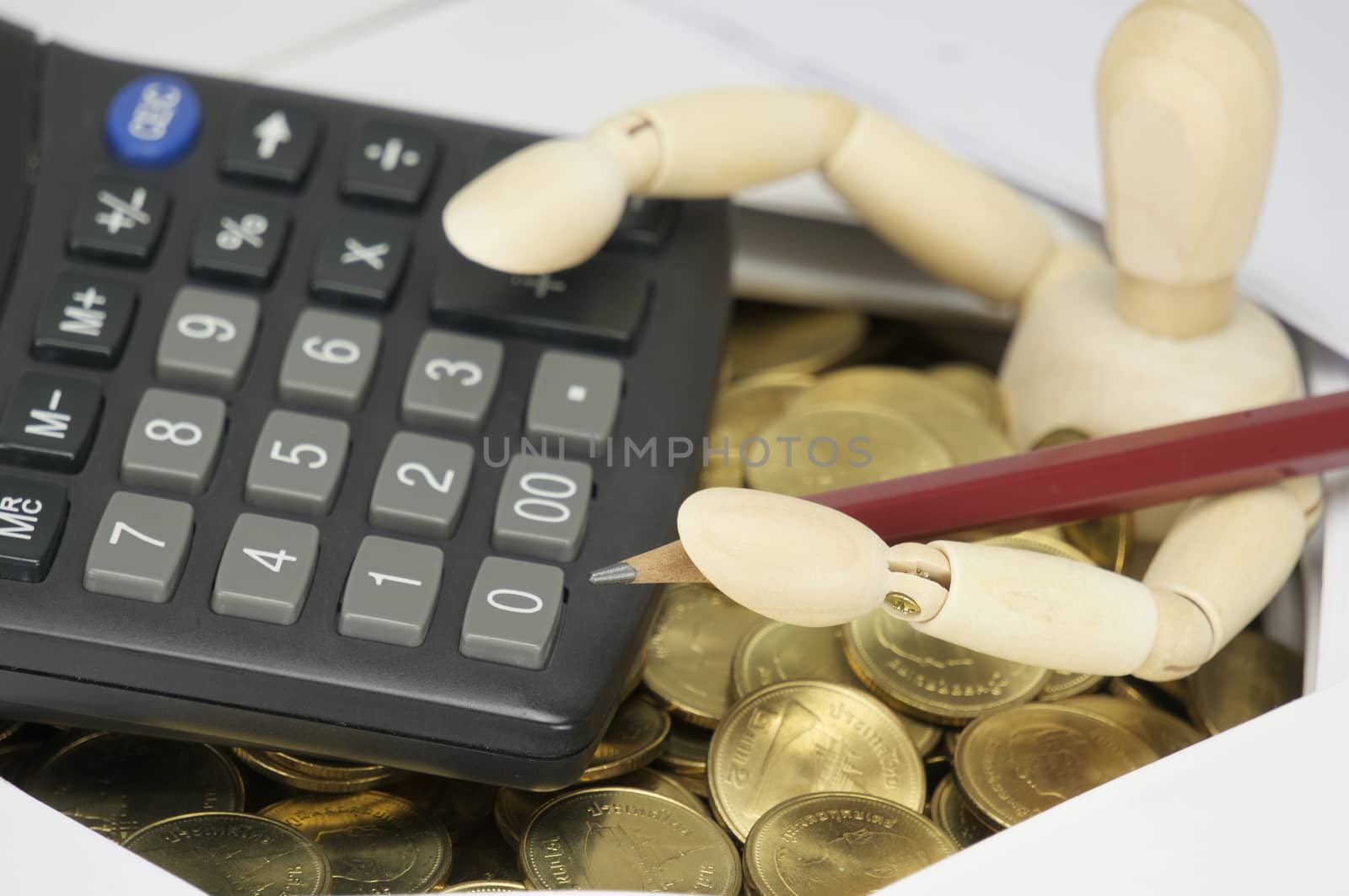 Wooden dummy holding pencil with calculator have surrounded by coins by eaglesky