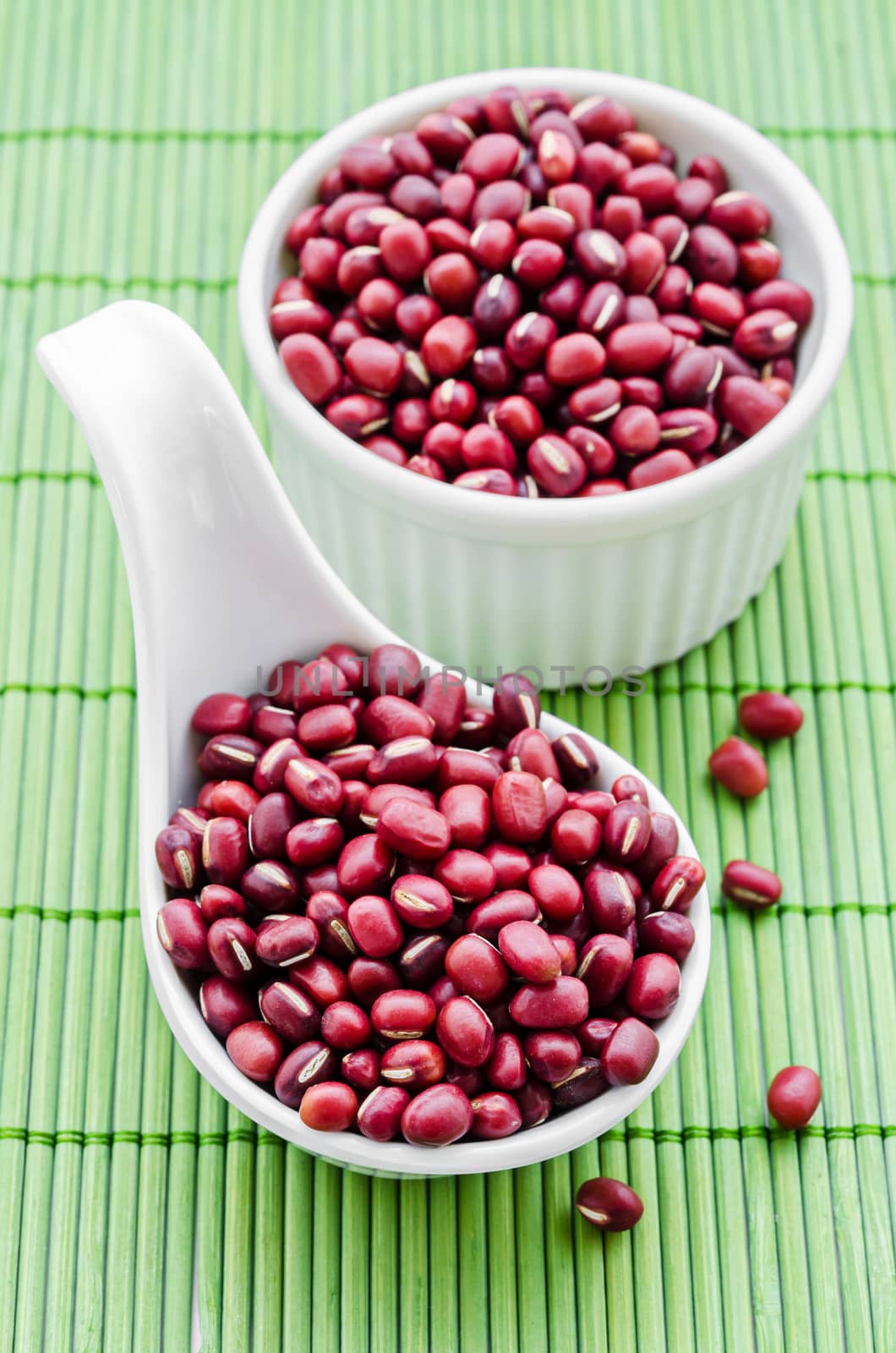 azuki beans , red beans in white spoon on green bamboo mat.