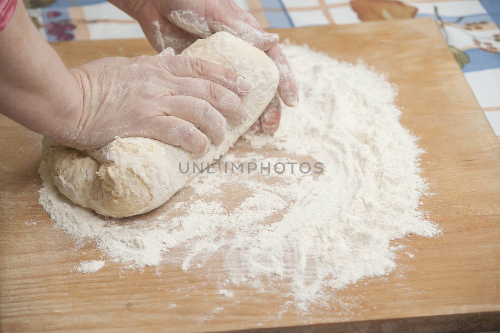 Women's hands preparing fresh yeast dough on wooden table