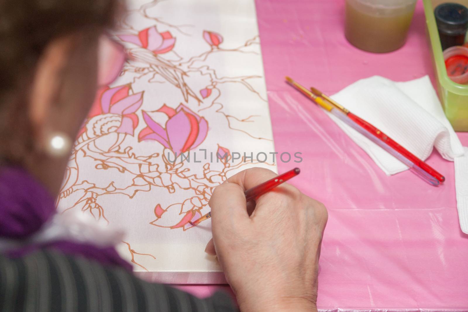 A woman hand with pencil is drawing picture with flowers