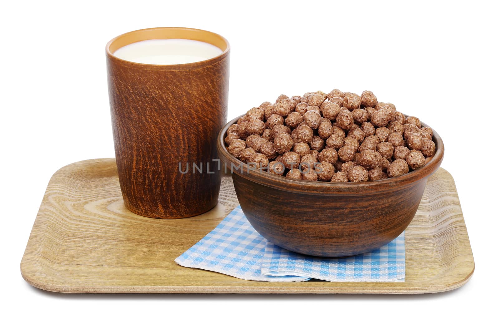 Chocolate cereal balls in a ceramic bowl and a mug with milk on a wooden tray with paper napkins, isolated on white background.