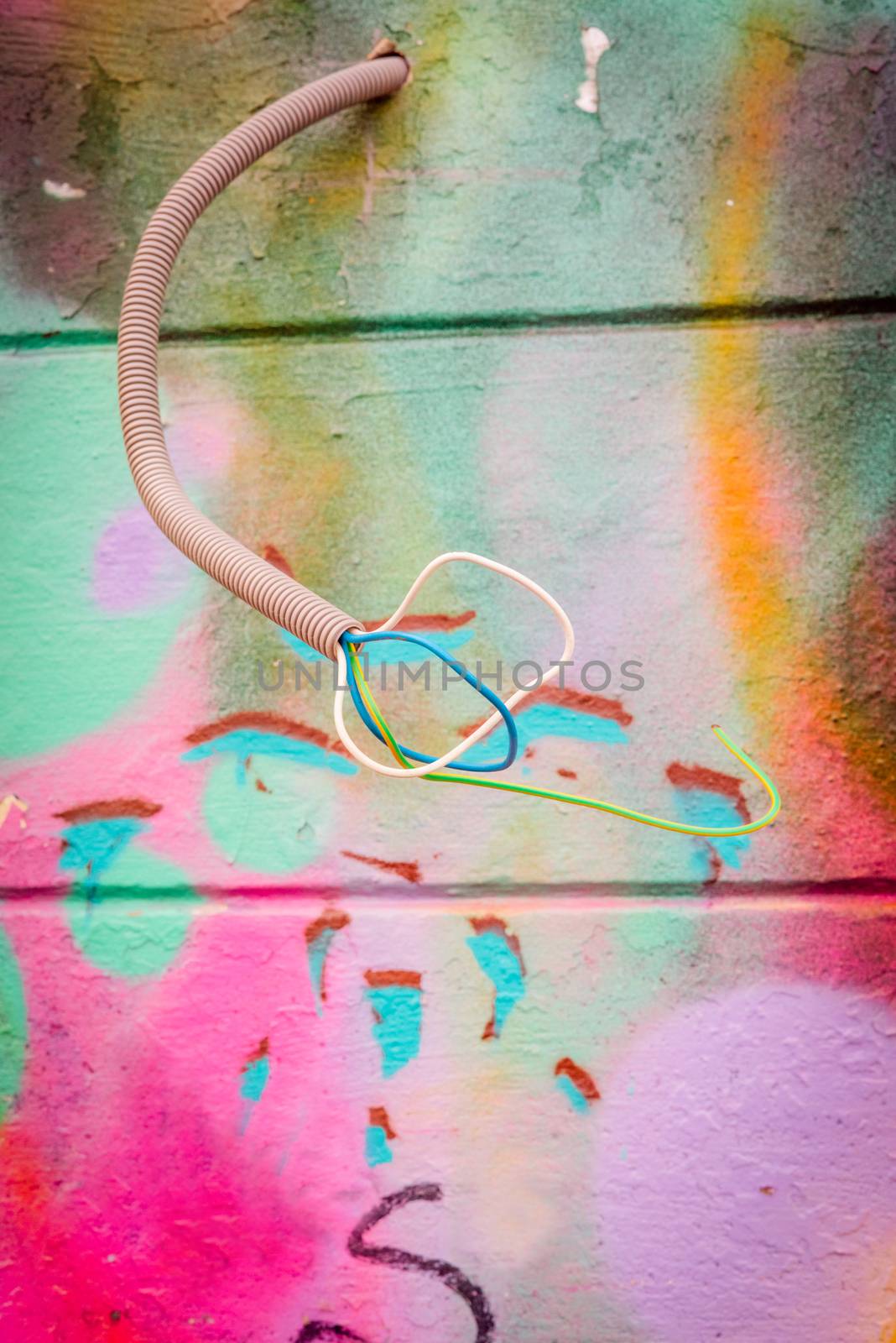 Wires coming out of a grungy wall with grafitti by Sportactive
