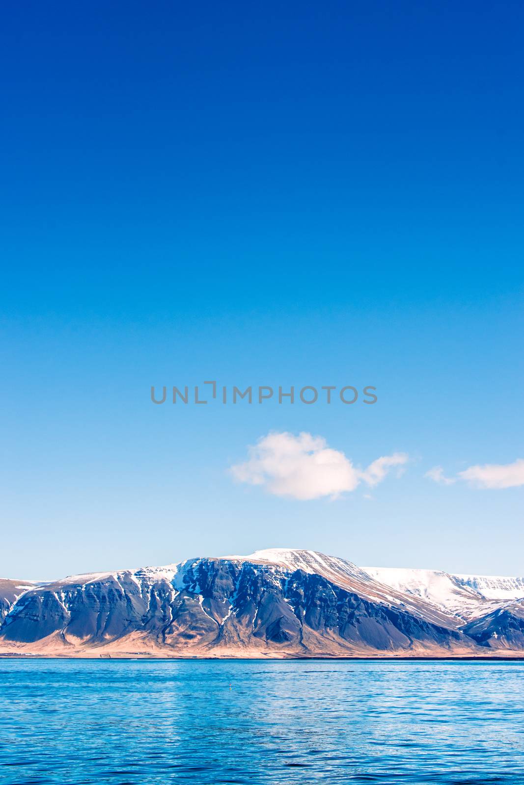 Idyllic mountain scenery by the ocean with white clouds