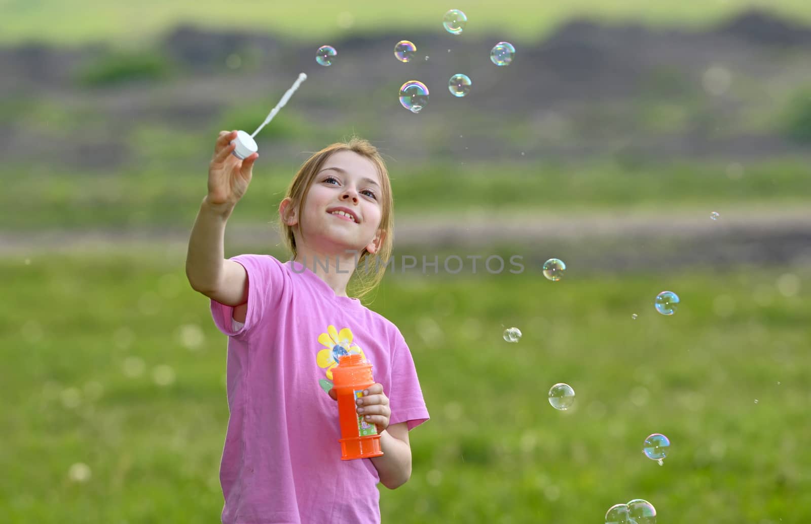 little girl play with soap bubbles on field