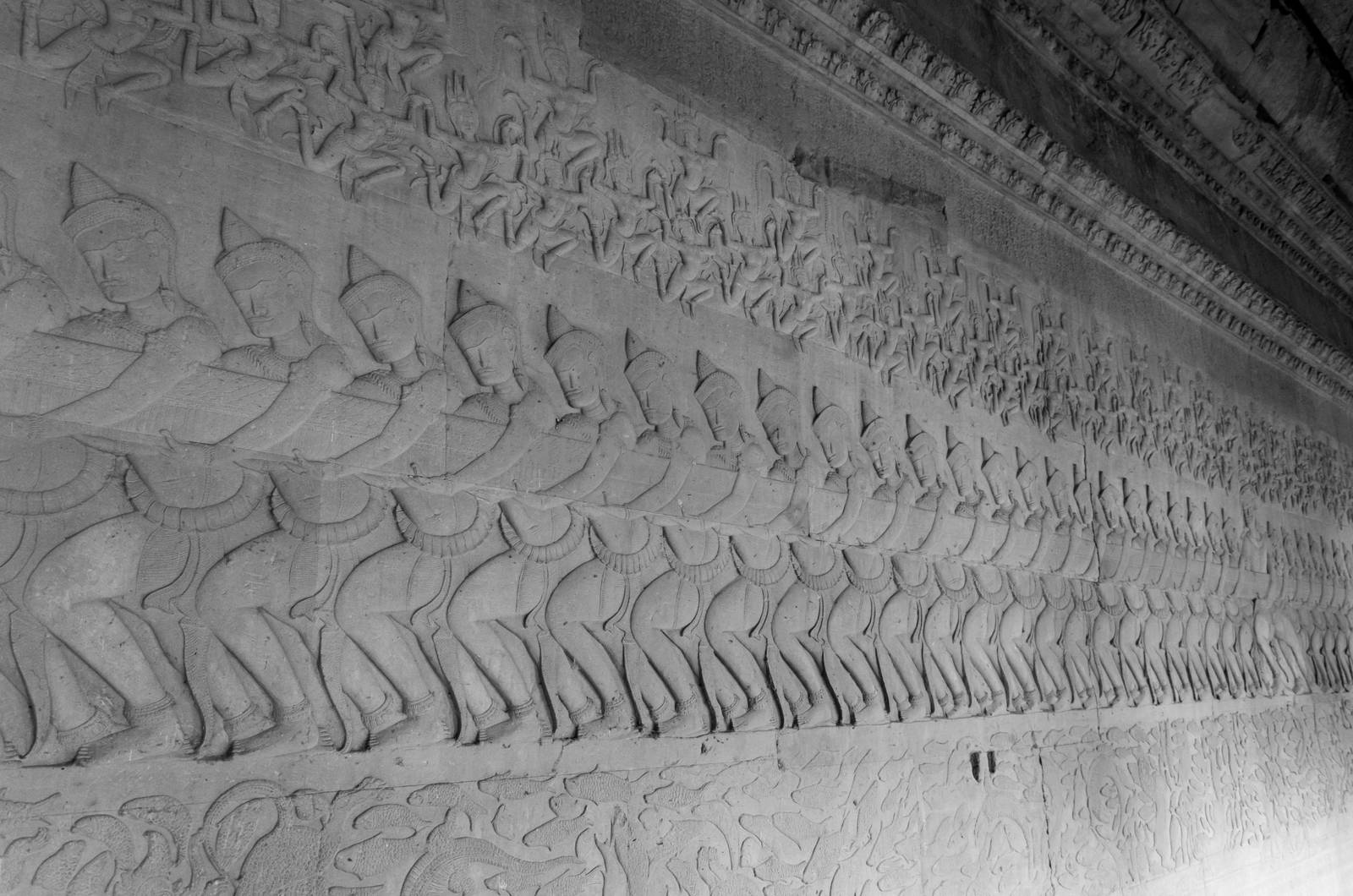 Ancient Khmer bas relief carving showing Hindu gods pulling on the snake Vasuki in the Churning of the Ocean of Milk legend, Angkor Wat Temple, Siem Reap, Cambodia