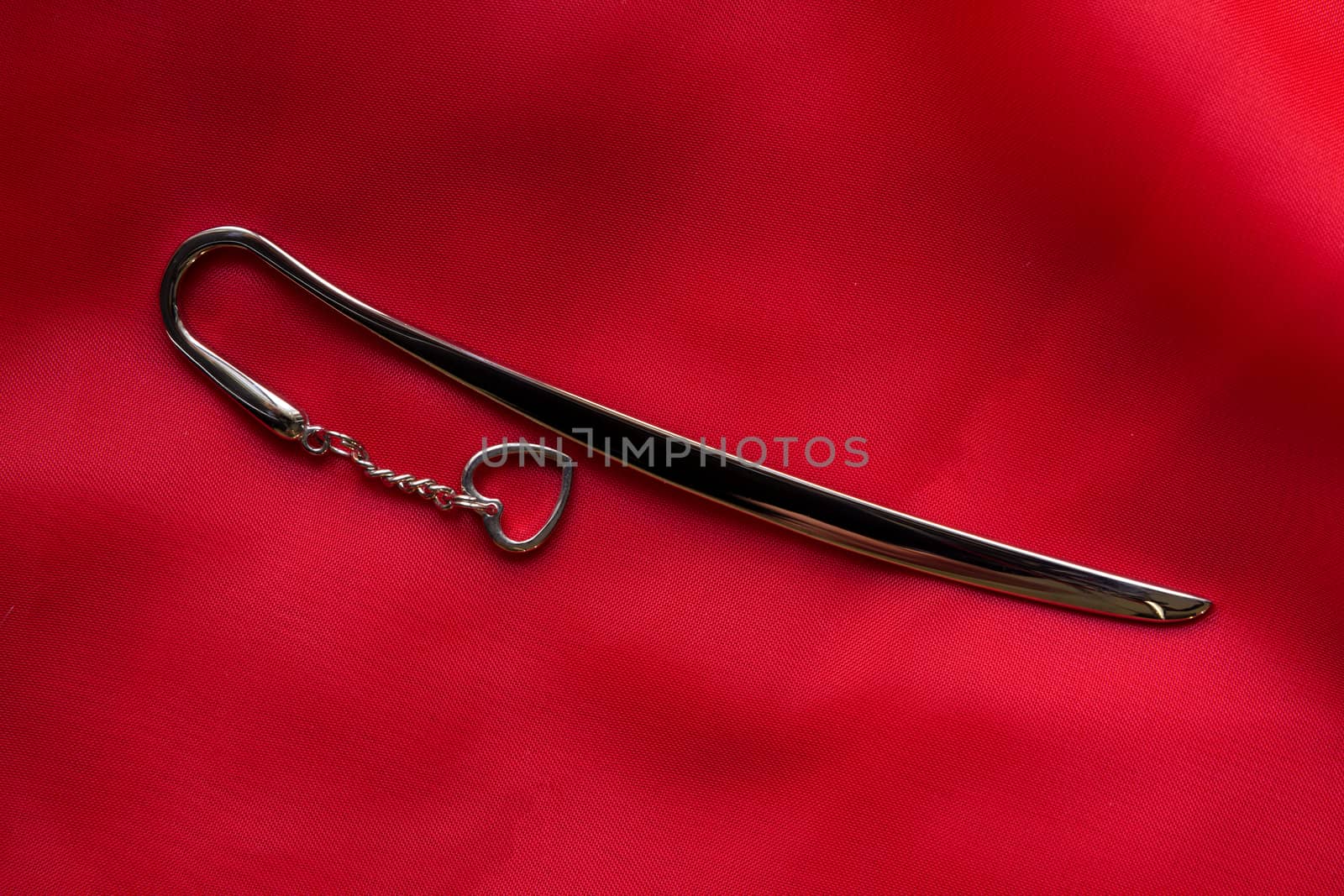 metal bookmark with heart symbol on delicate red silk background