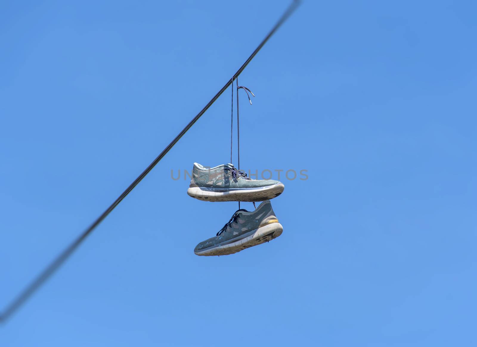Shoes dangling on a cable over the street have many explanations, from celebrating one's birthday or wedding and making fun of drunk friends, to marking a location of drug dealers and bullying.