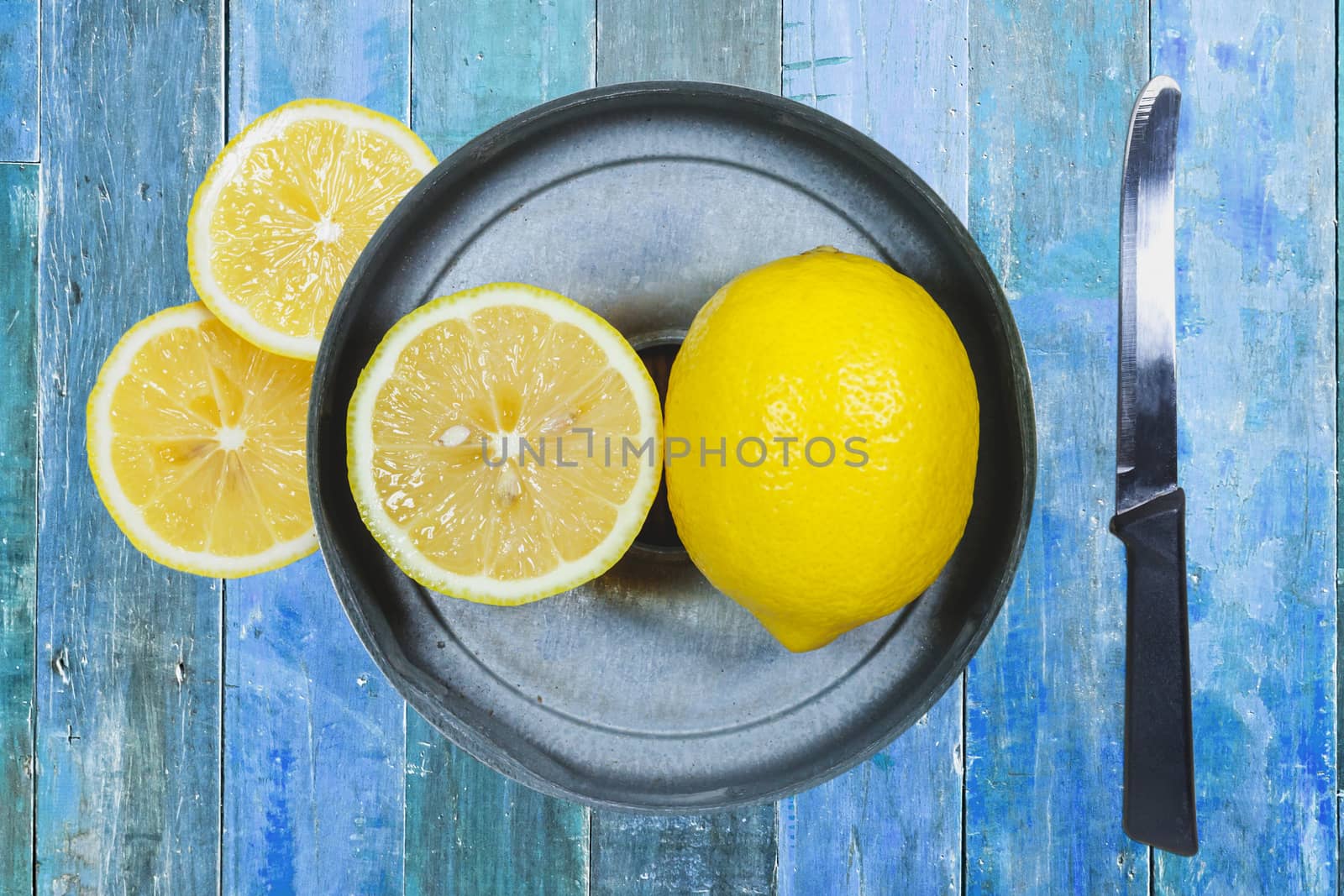 Sliced lemons with knife isolated on blue wood background.