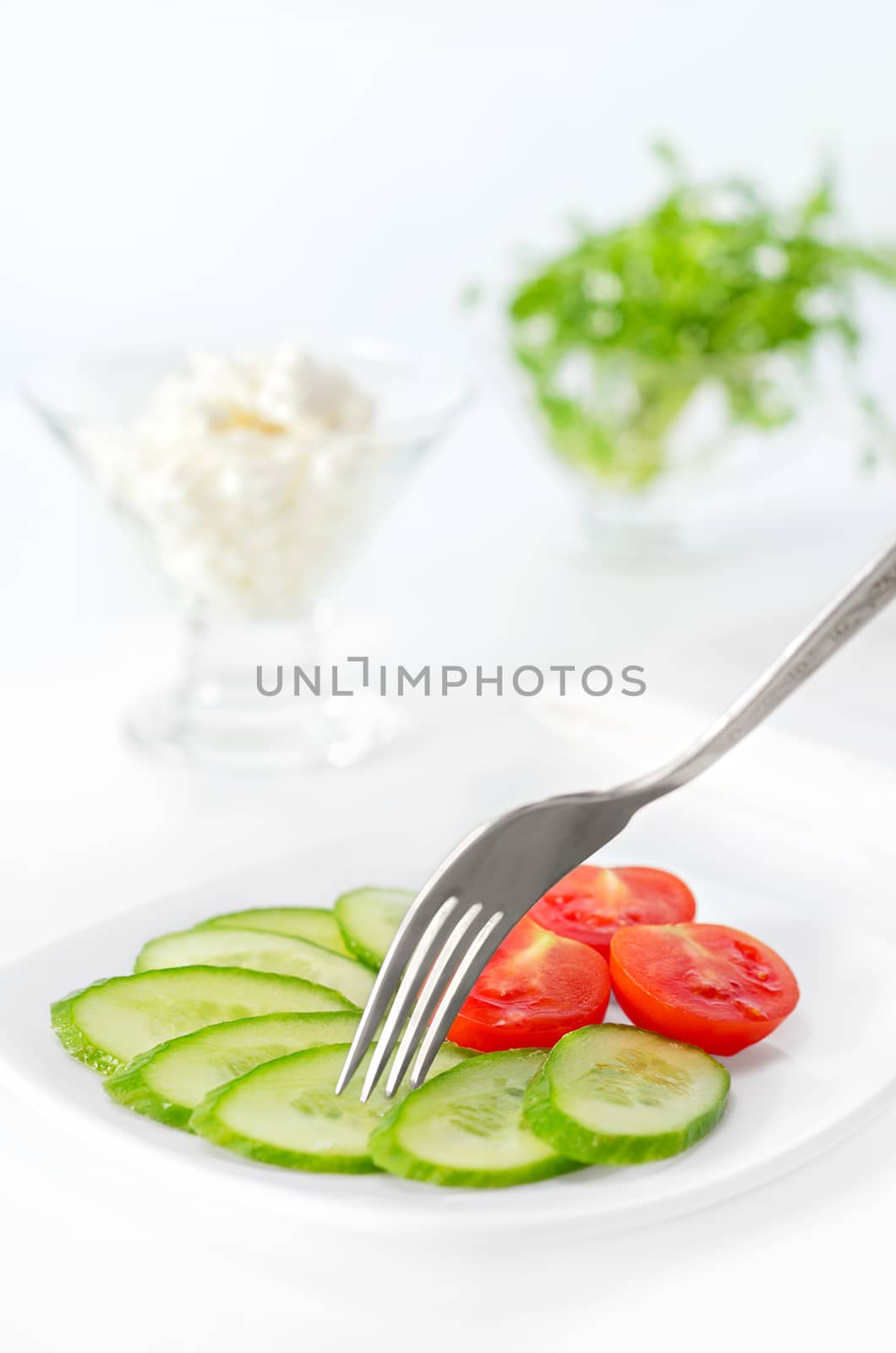 Sliced tomato and cucumber on a plate. by Gaina