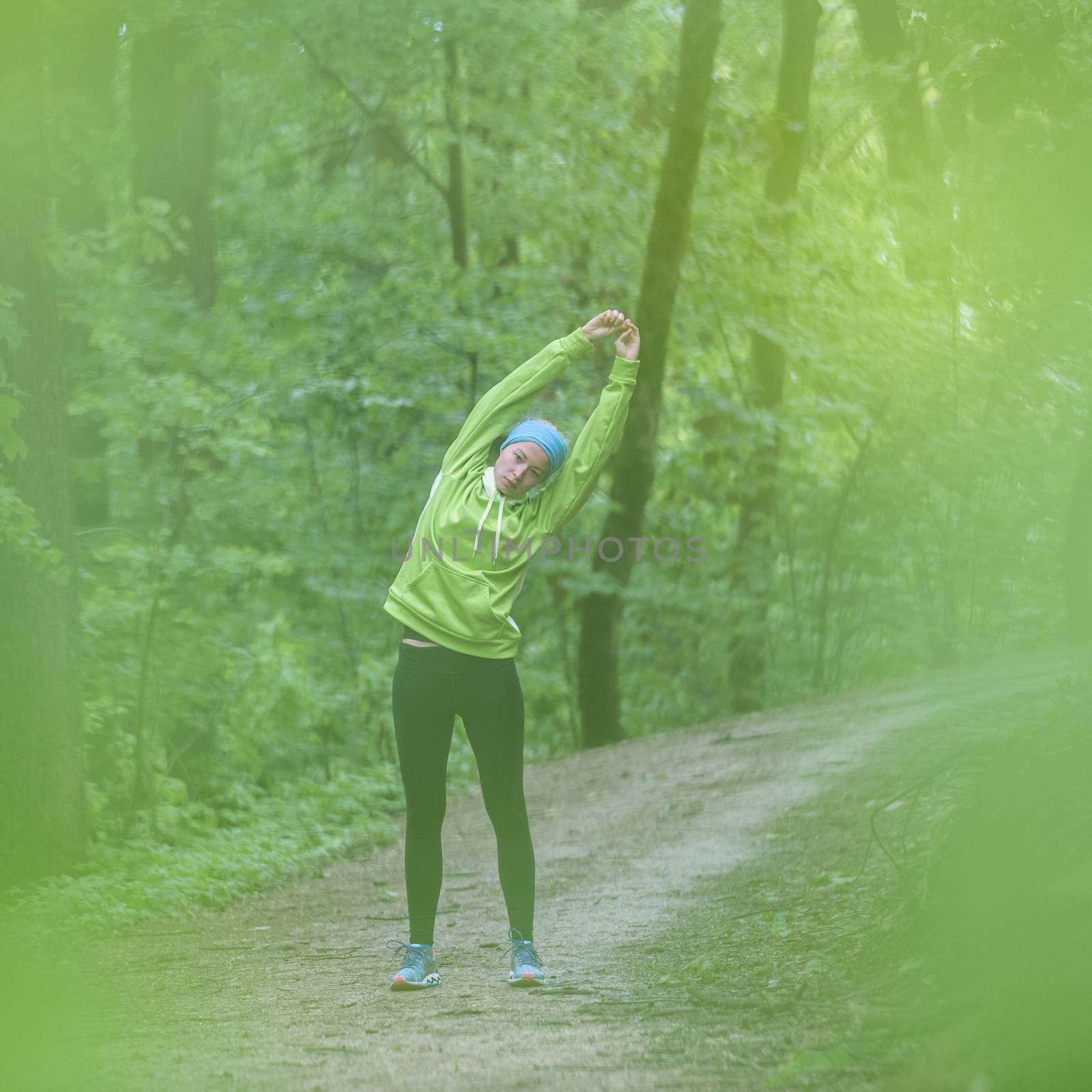 Sporty young female working out in forest.  Female runner during stretching exercise in nature. Fitness model outdoors. Weight Loss. Healthy lifestyle. 