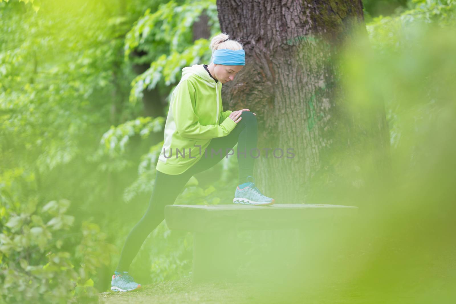Sporty young female working out in forest.  Female runner during stretching exercise in nature. Fitness model outdoors. Weight Loss. Healthy lifestyle. 