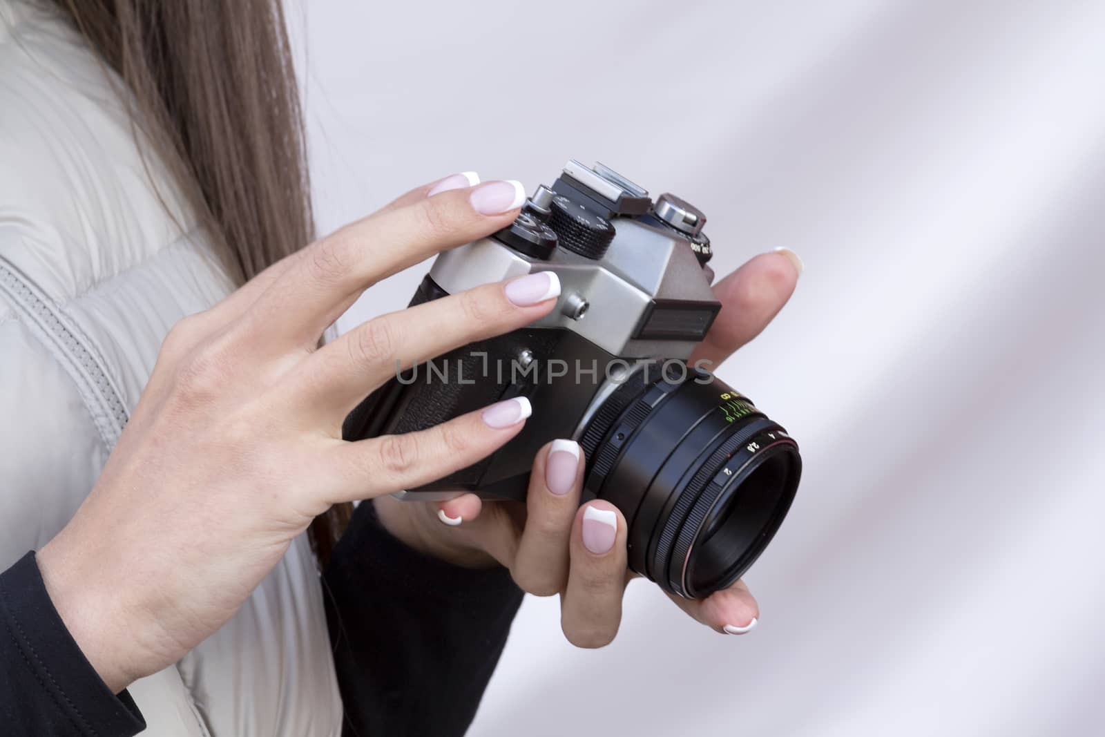 the girl with the French manicure is holding the vintage  camera