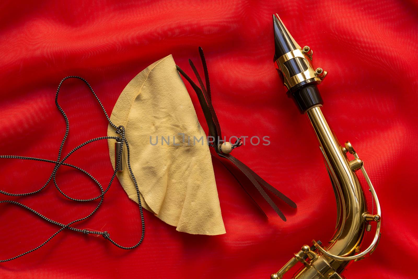 Suede brush and saxophone mouthpiece on a red background