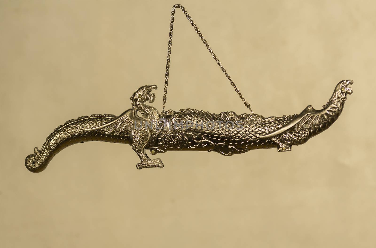 decorative carved dagger with heads of dragons in a sheath on a gray background