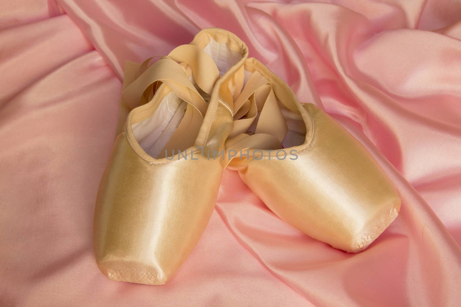 Ballet shoes on silk pink background