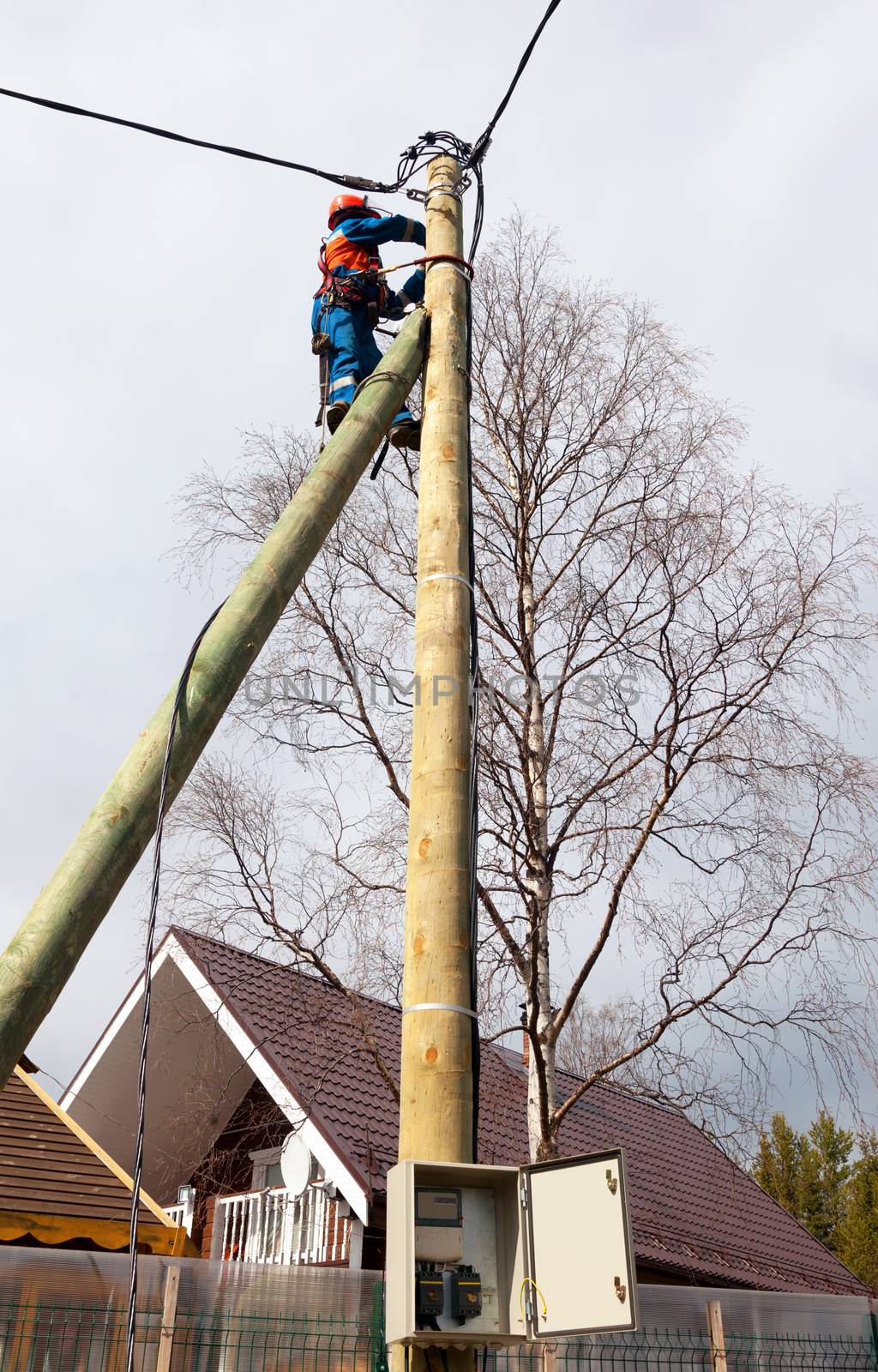 Electrician connects wires on a pole in a country house. Cottage