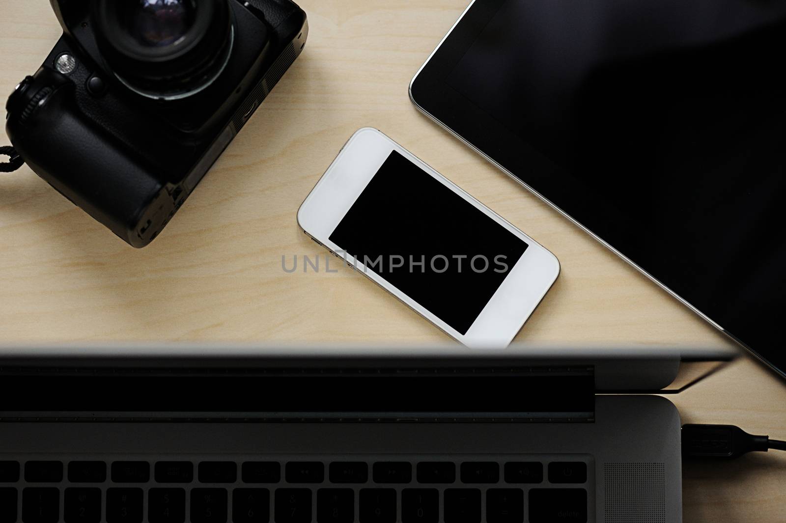 Phone, tablet, camera and laptop on wooden table