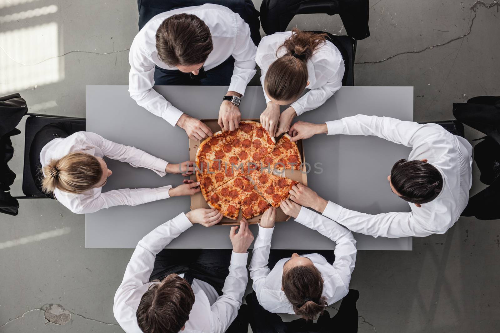 Business team eating pizza in office sitting around the table