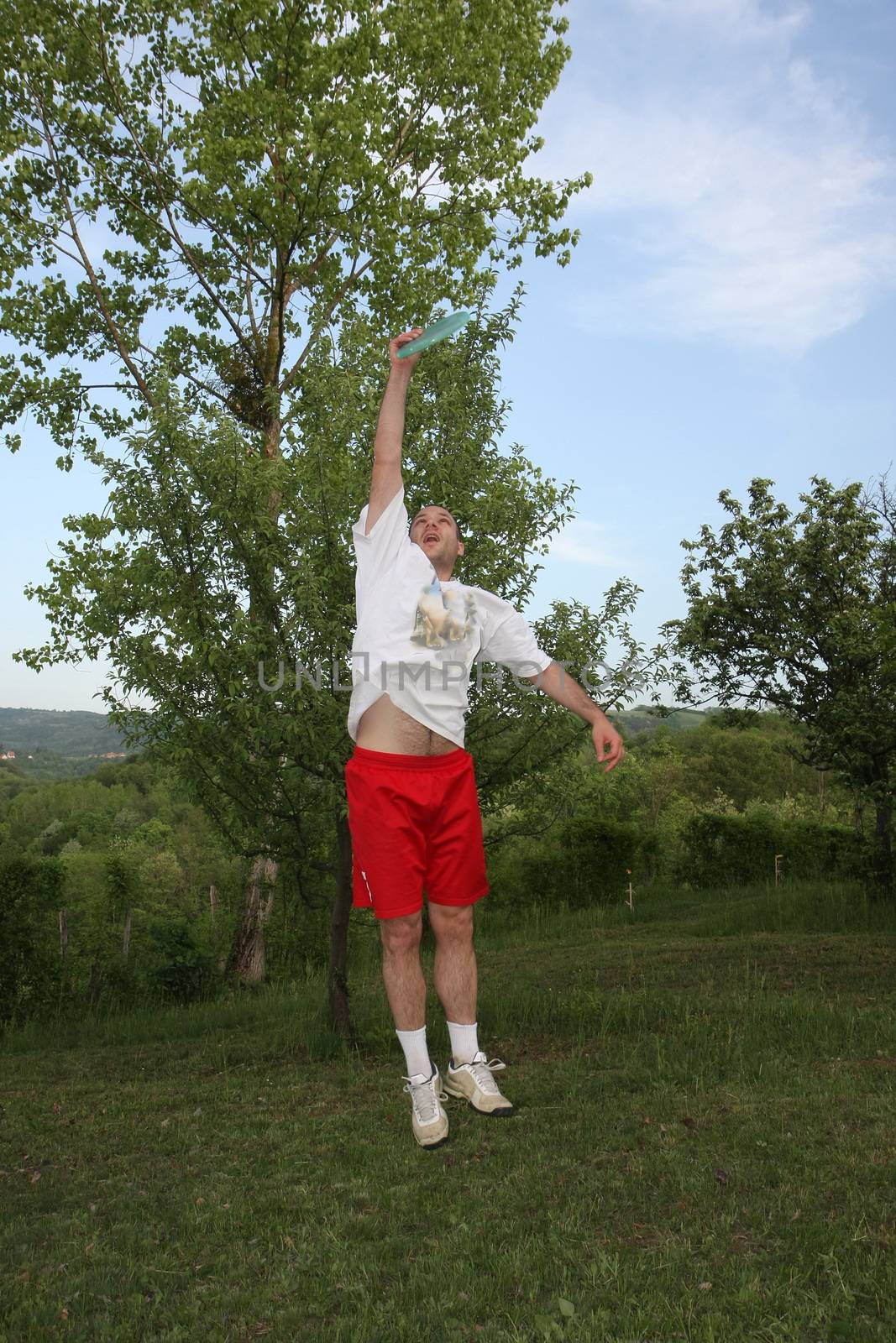 Young man in red and white playing fresbee in nature