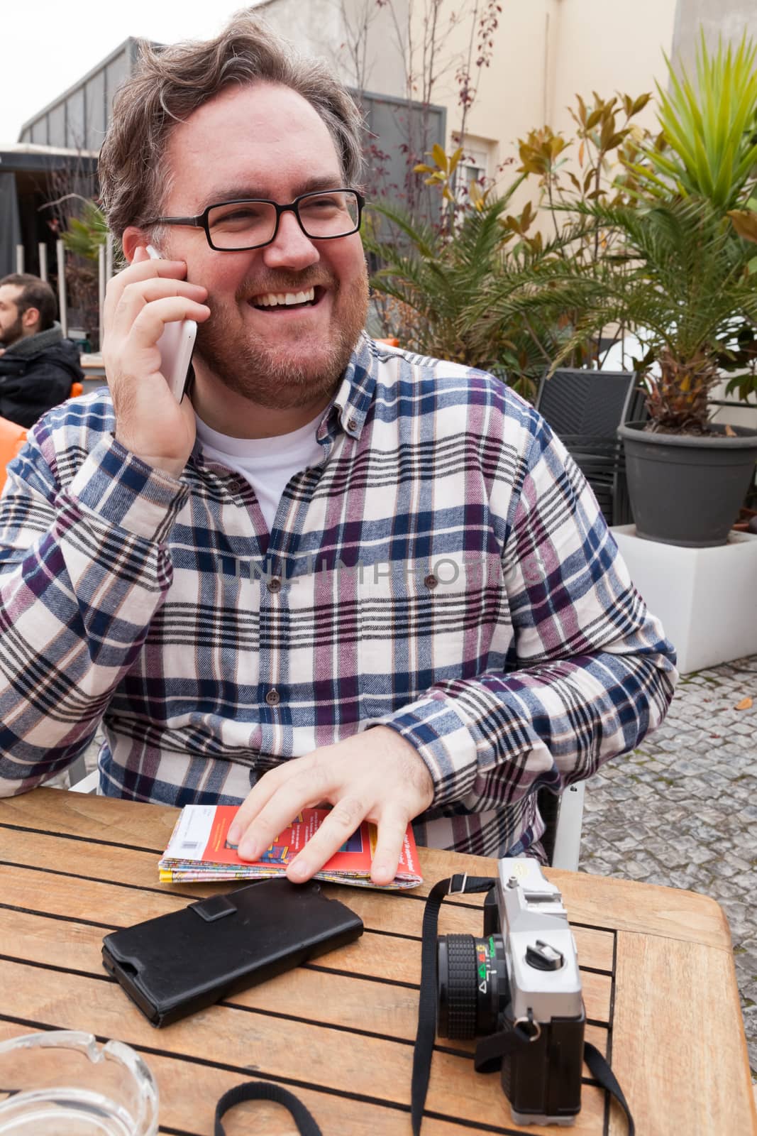 A young man with glasses searching around and laughing and talking by phone