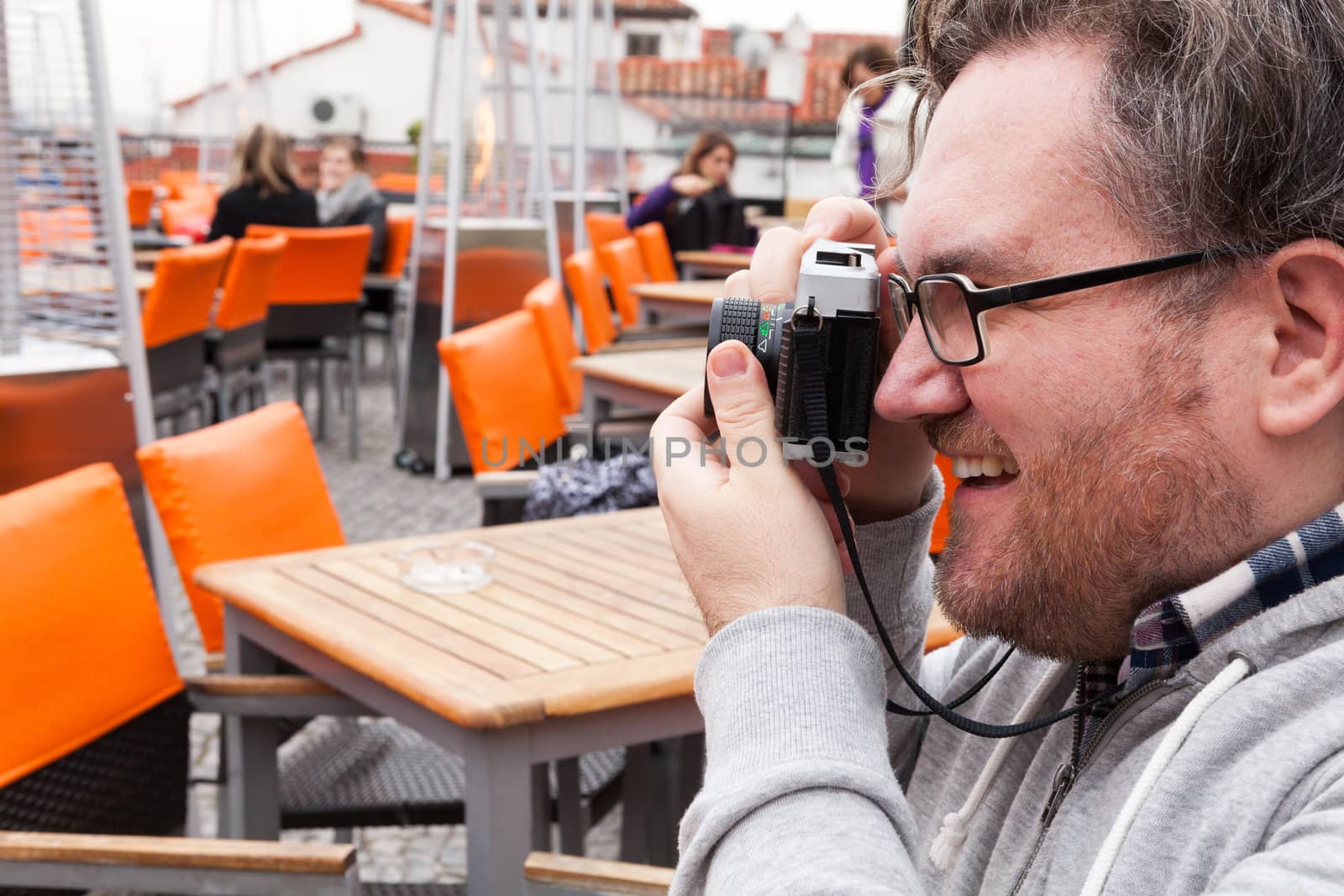 Young traveller man with glasses looking and laughing is having fun with a vintage camera