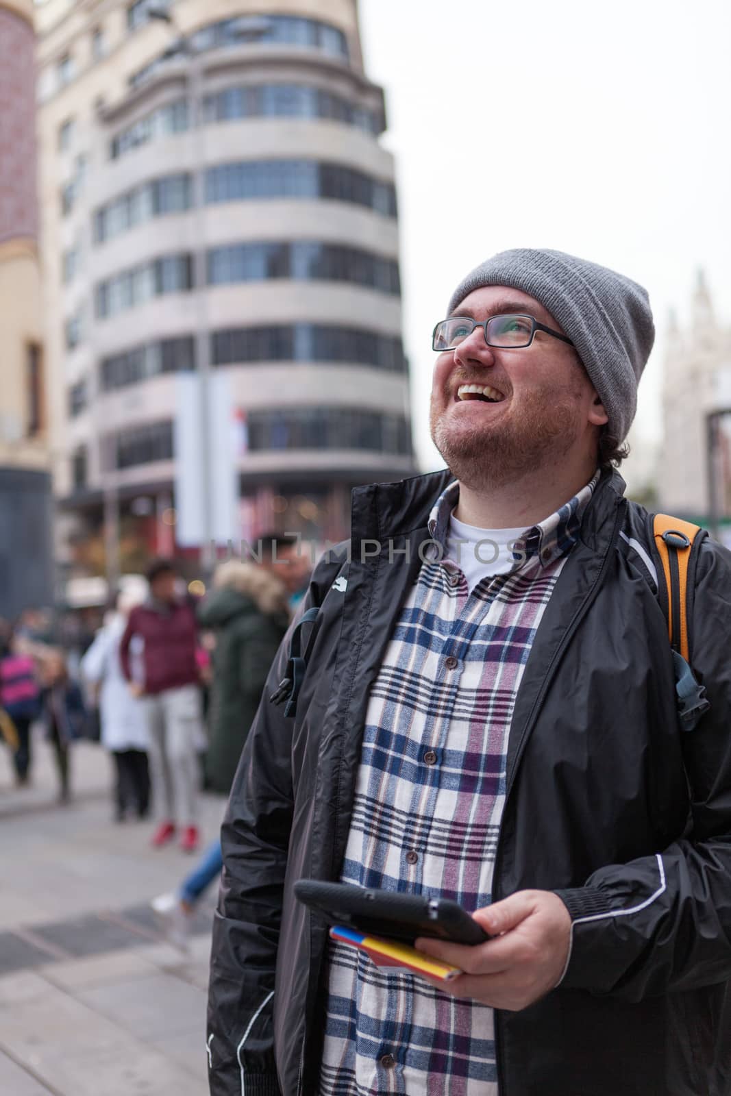 Young traveller man with glasses and a hat  looking for a place in a map looking up