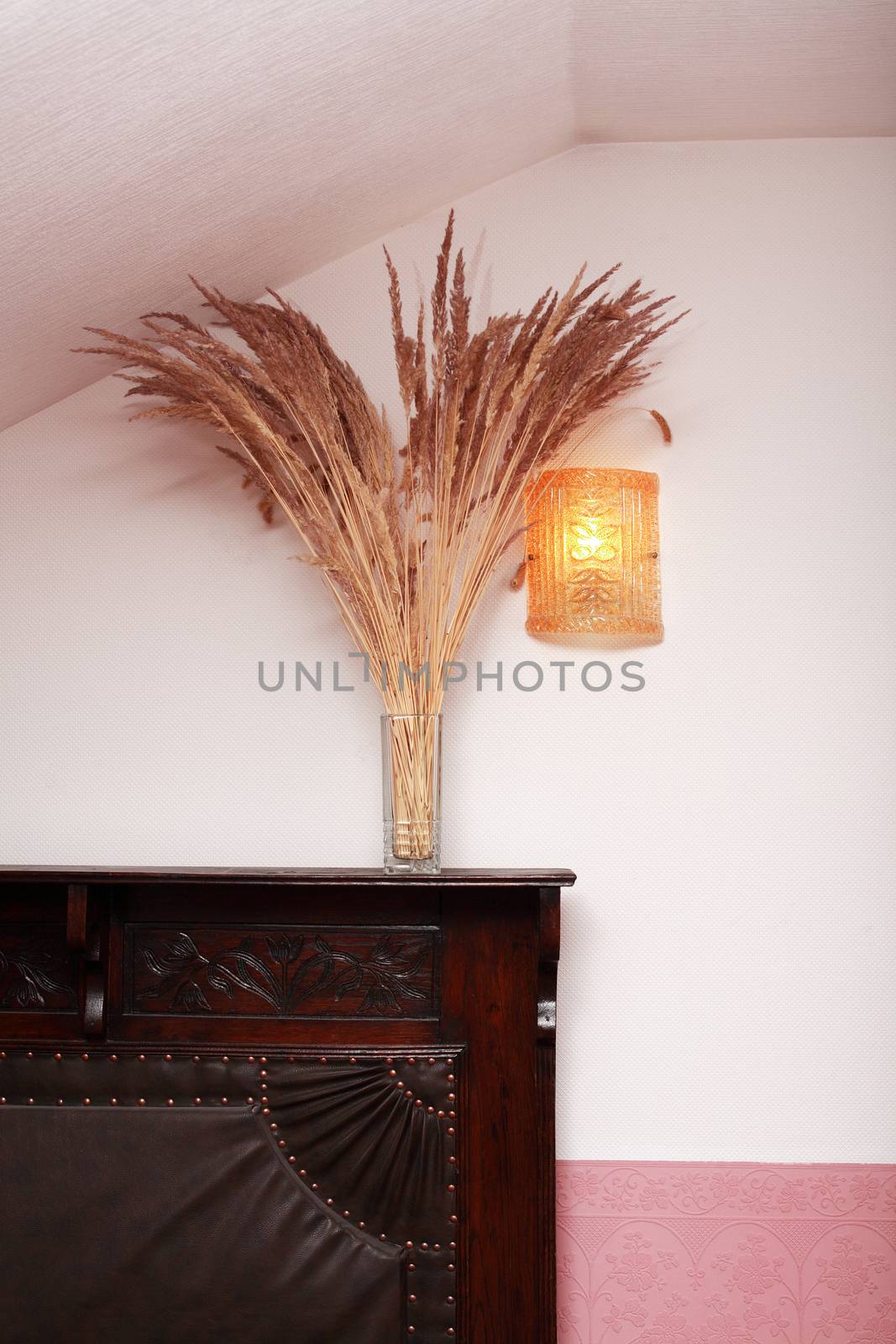 Home interior with bunch of dry wheat on old leather sofa