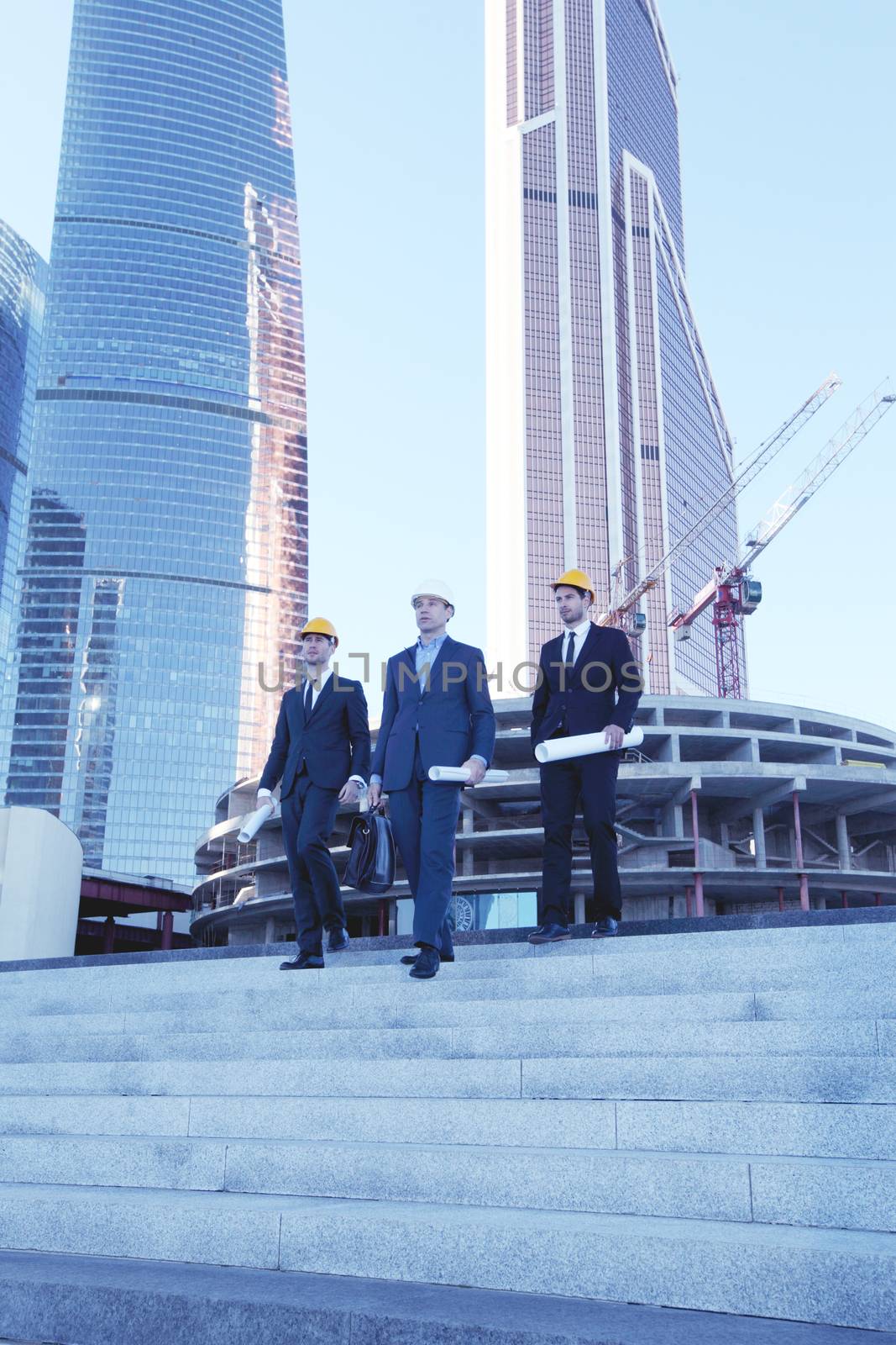 Architects with blueprint at skyscrapers background