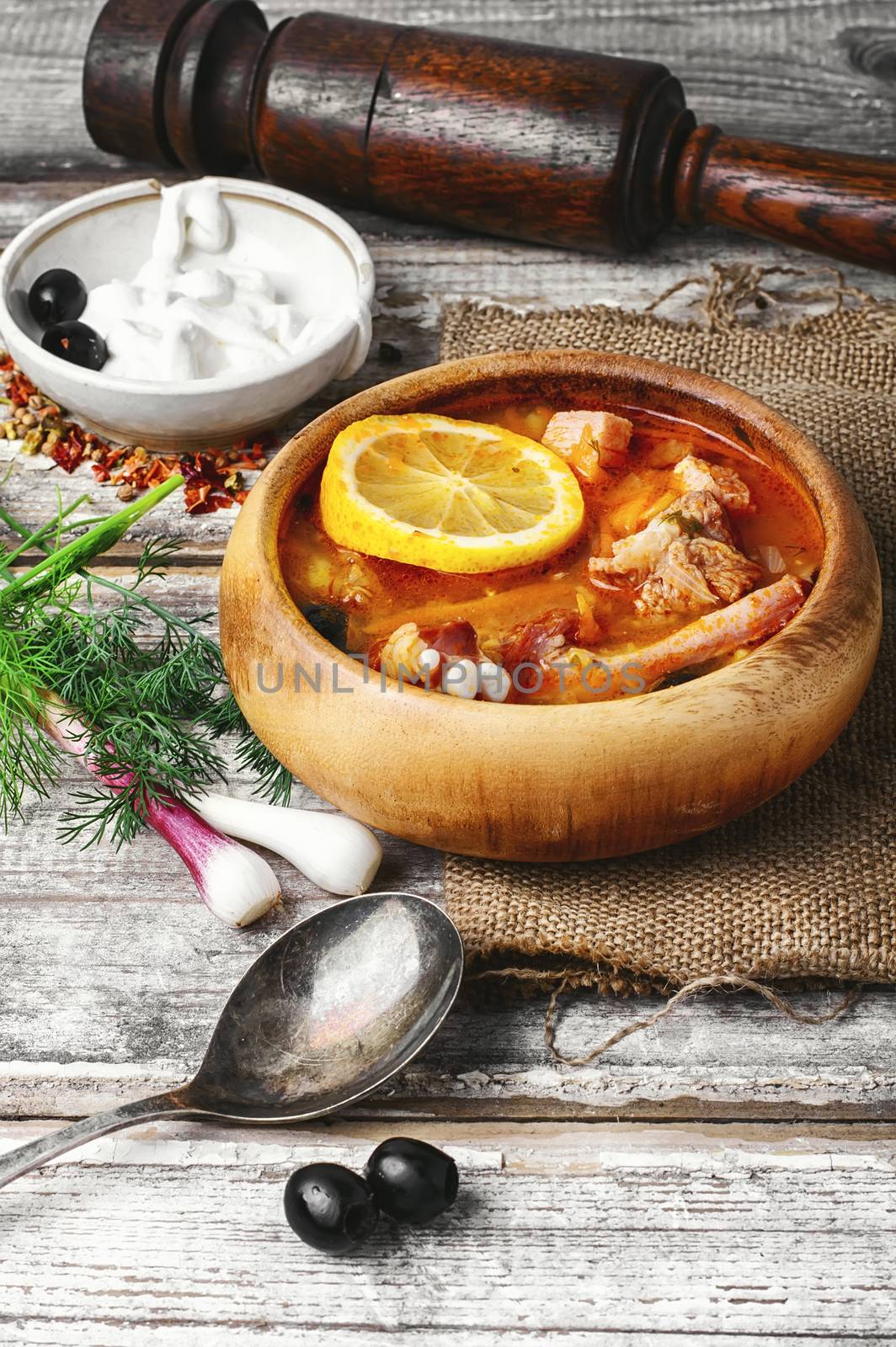 Traditional solyanka with smoked meats in wooden plate