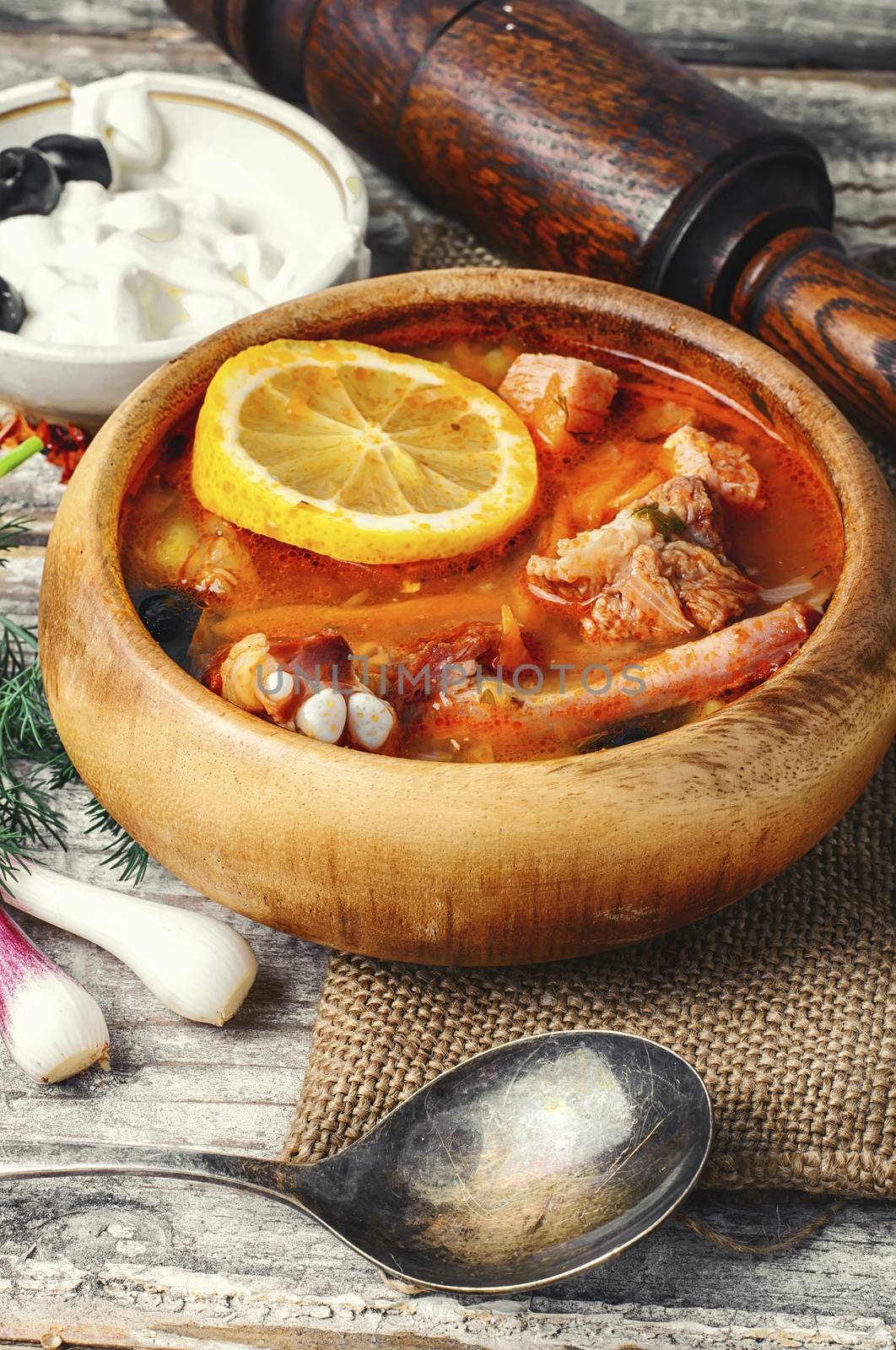 Traditional solyanka with smoked meats in wooden plate