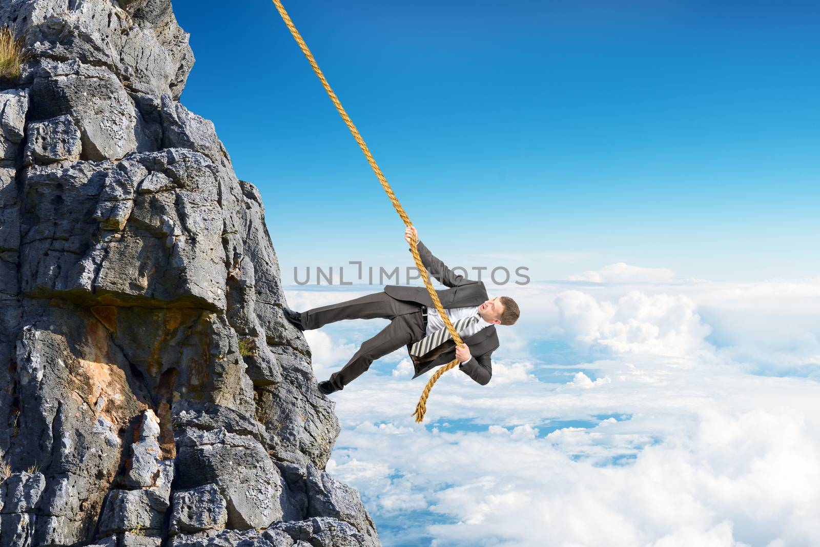 Businessman climbing on mountain with rope  by cherezoff
