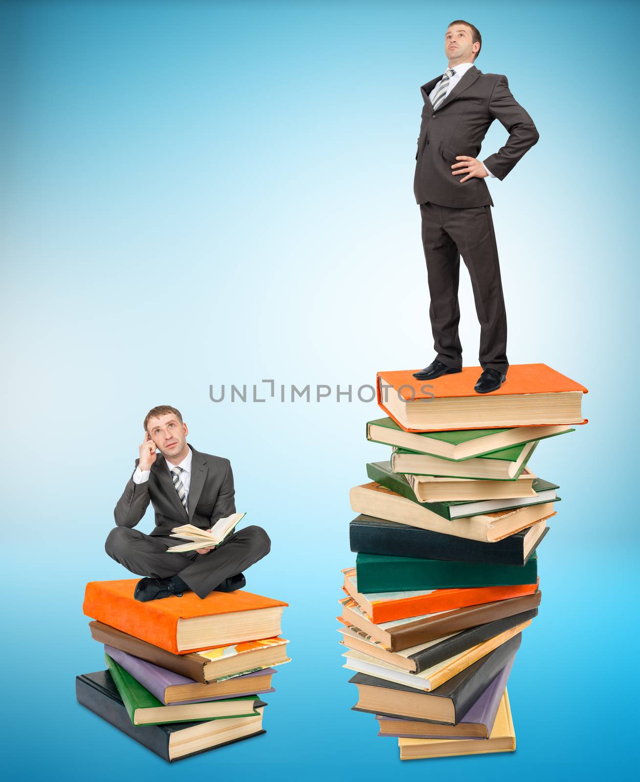 Proud businessman standing on stack of books with another man sitting on books