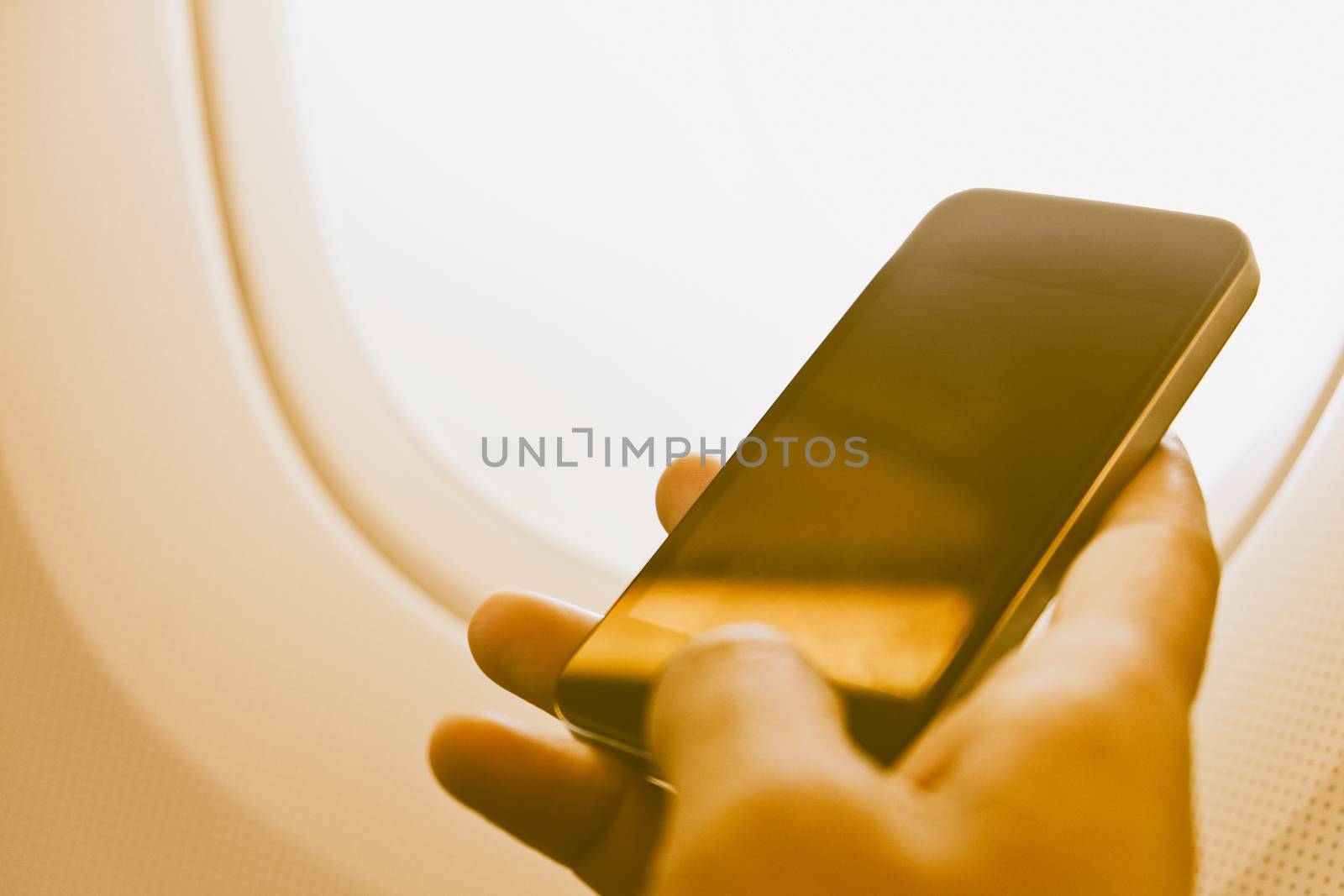 close up of business man siting near airplane window and watching his phone, Business communication