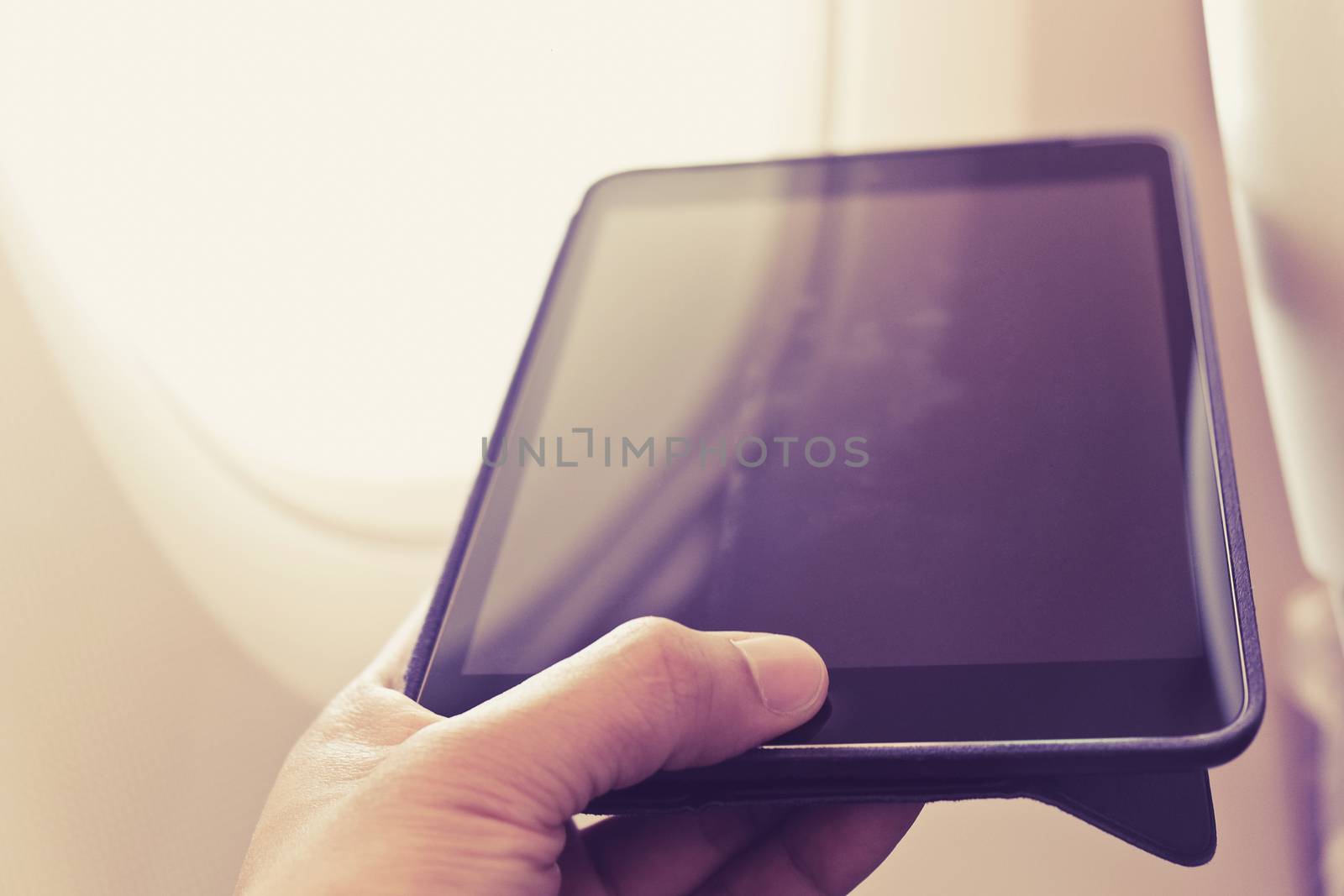 close up of business man siting near airplane window and using his digital tablet, Business communication