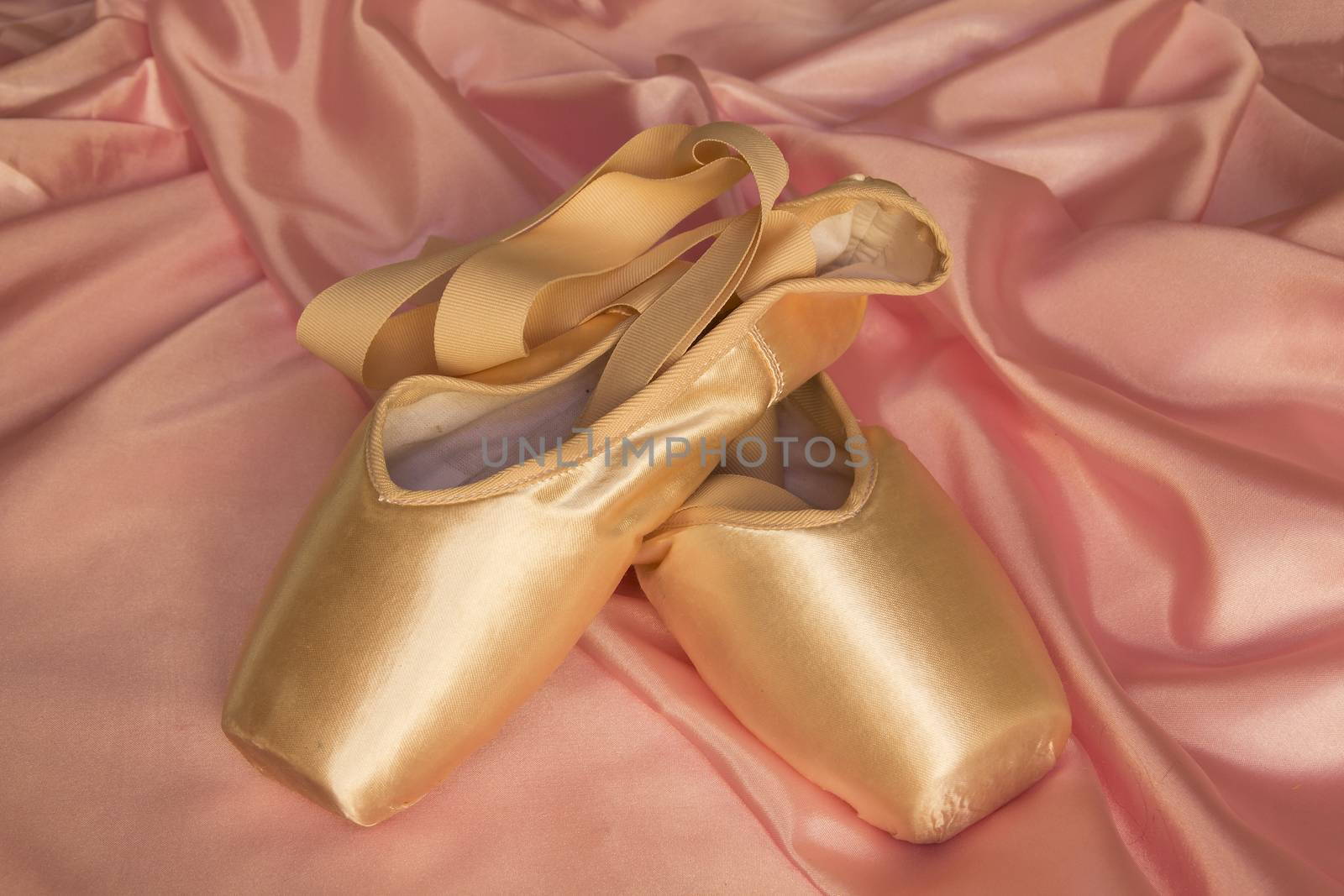 Ballet shoes on delicate pink silk background