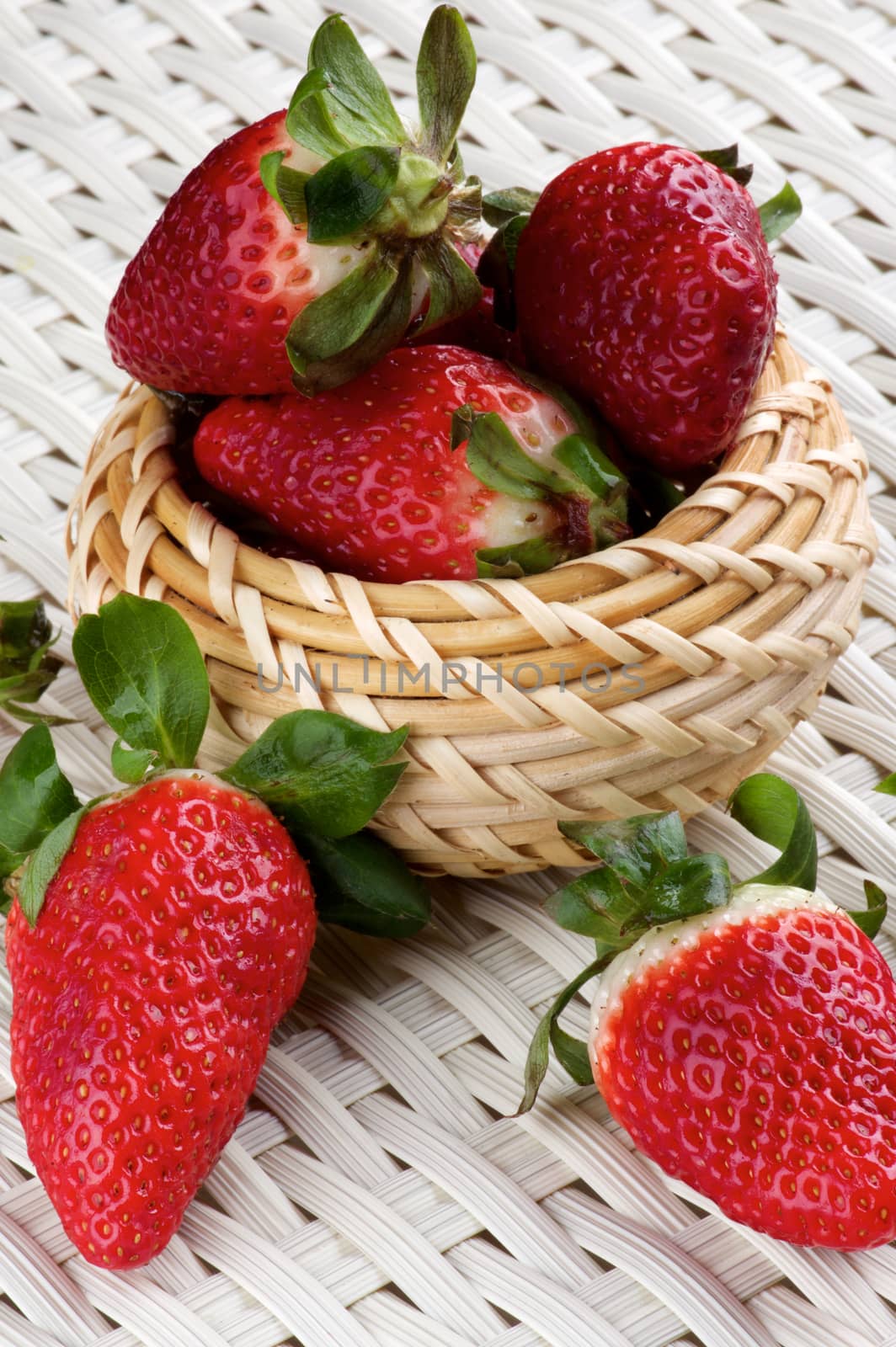 Heap of Fresh Ripe Strawberries in Wicker Bowl closeup on White Wicker background