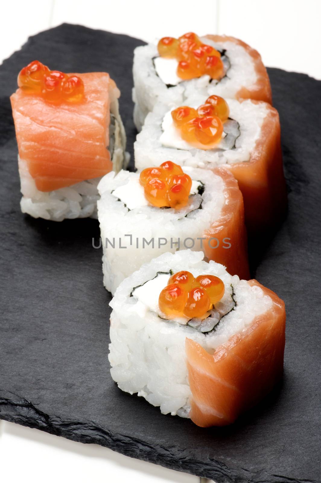 Delicious Sushi with Smoked Sliced Salmon and Gourmet Red Caviar on Stone Plate closeup on White Plank background