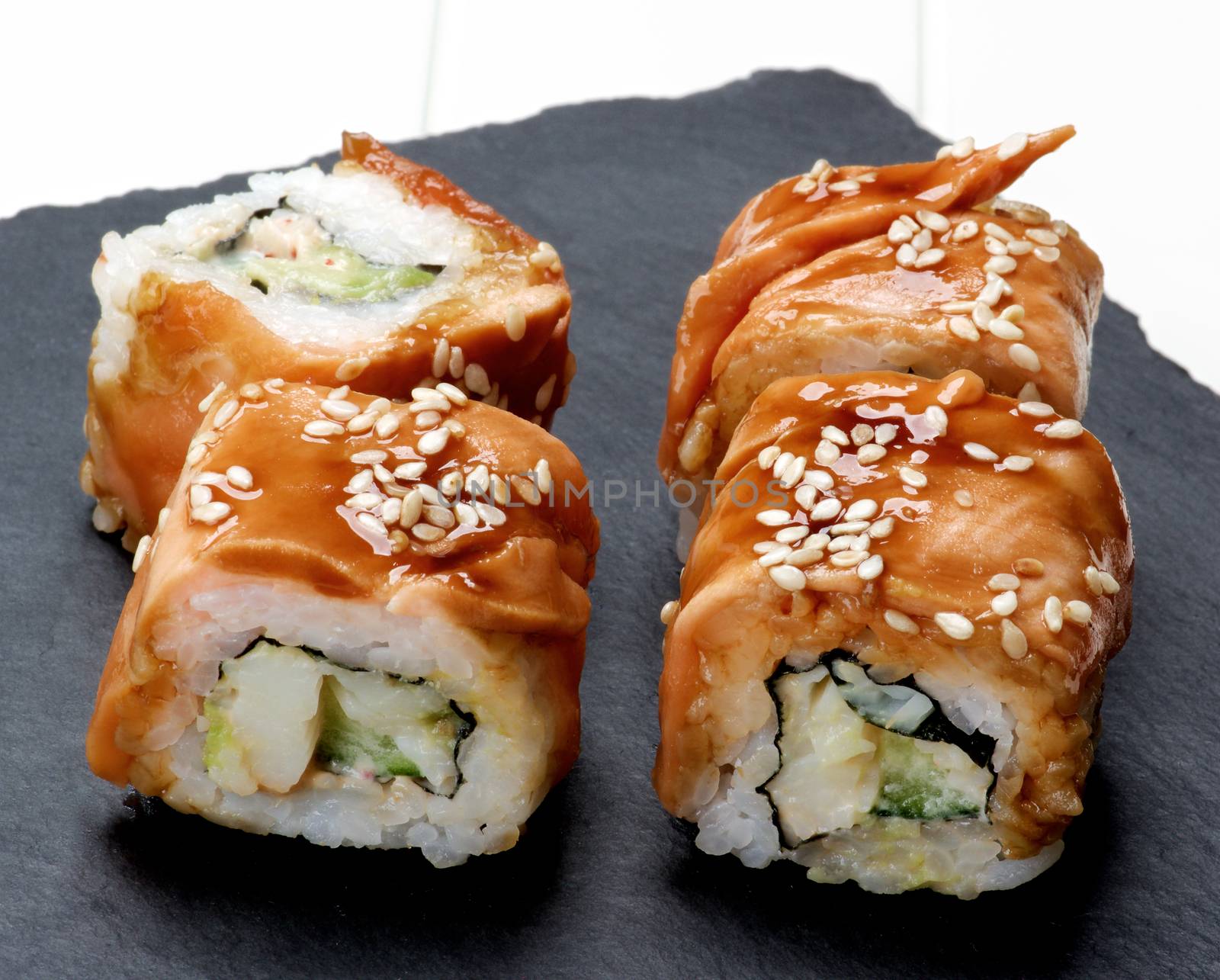 Delicious Smoked Eel Sushi with Sesame Seeds on Stone Plate closeup on White Plank background
