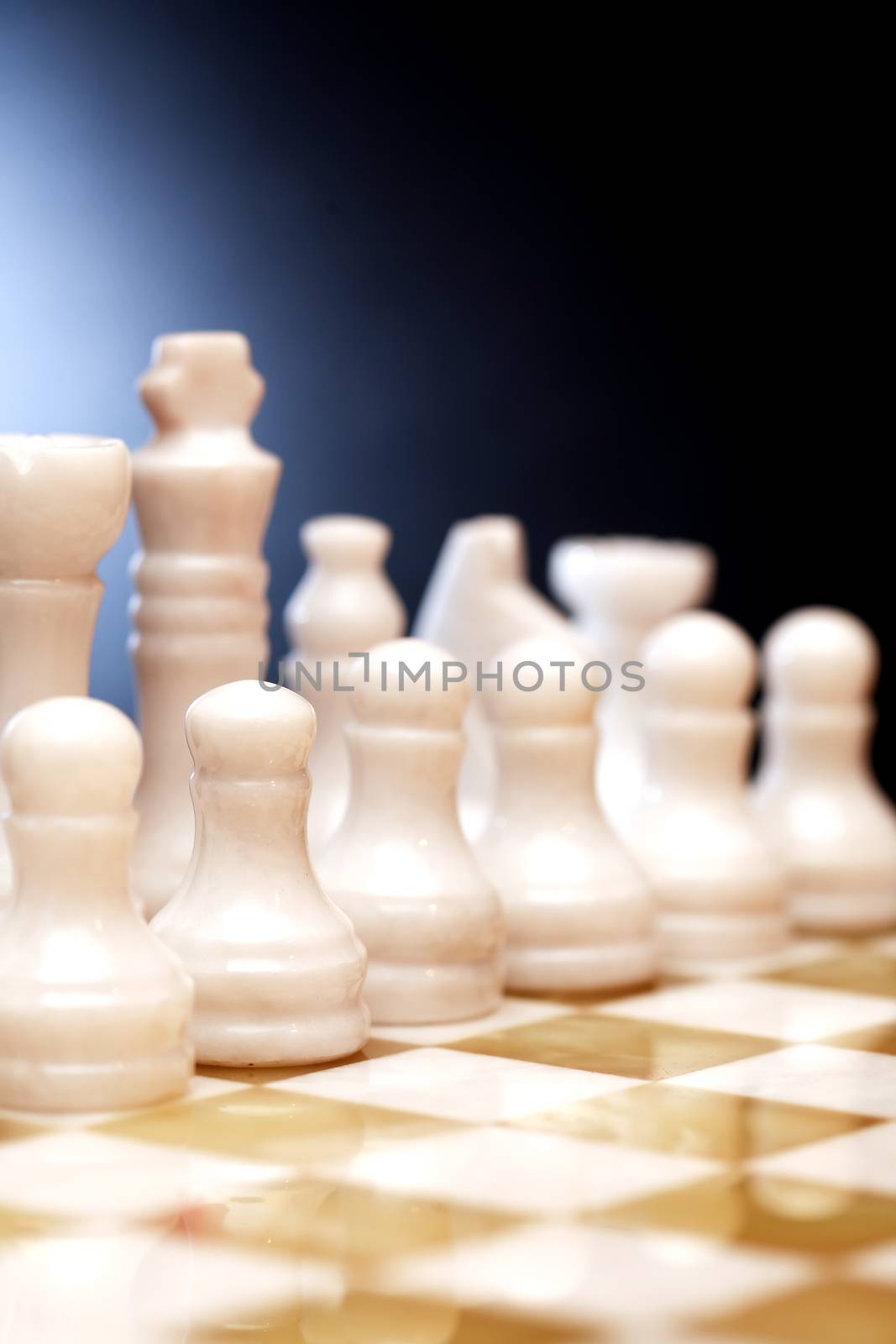 Set of chess pieces made from Onyx on board against dark background