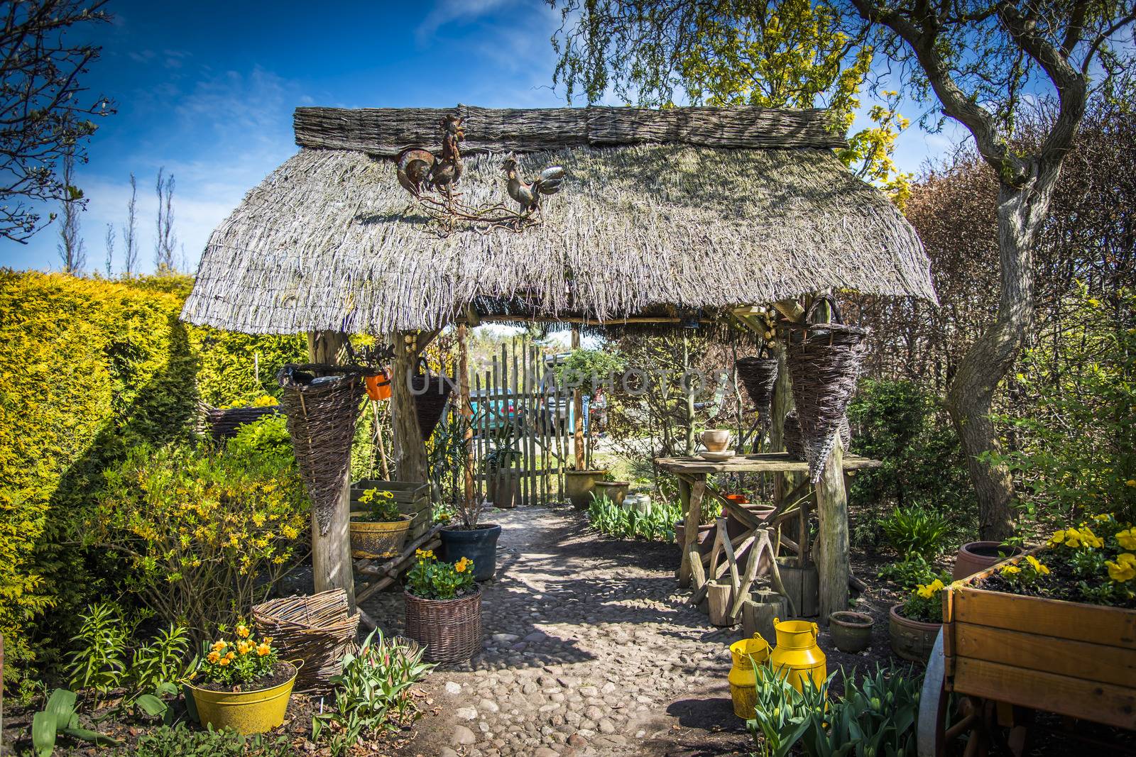 Old gazebo with thatched roof surrounded by plants