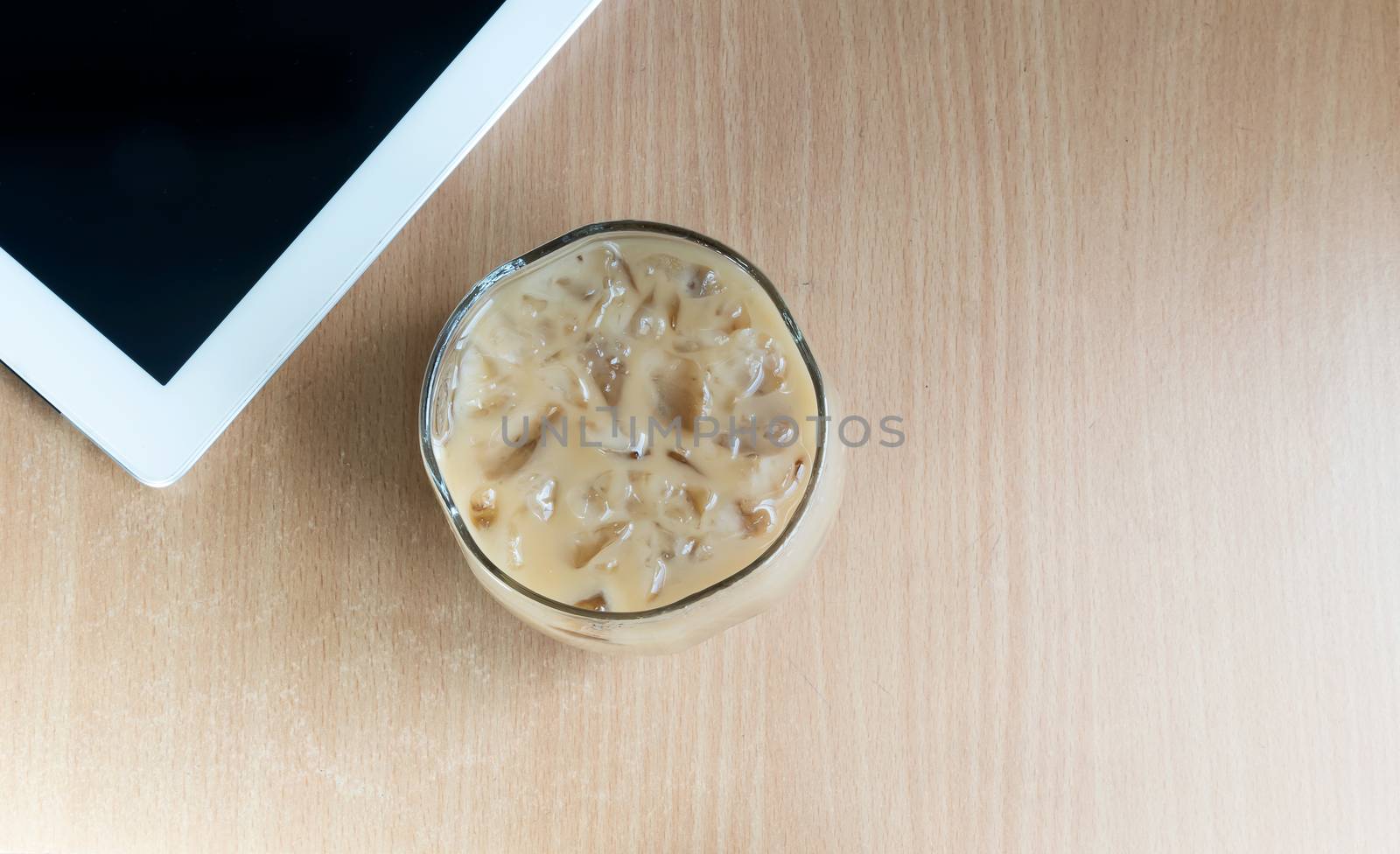 Ice coffee mugs and tablet placed on a wooden table.