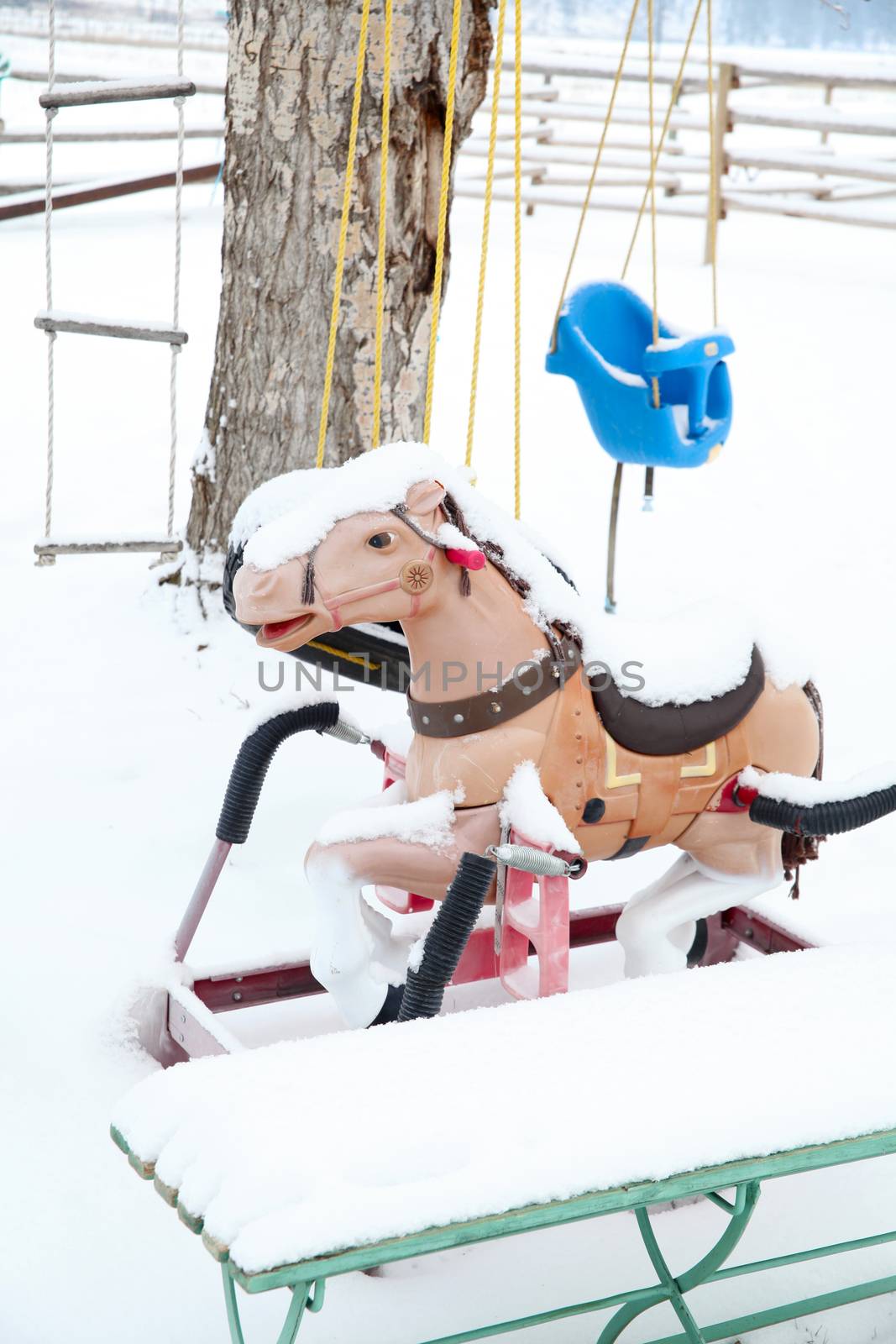 Snow covered outdoor swing, ladder and bouncy horse