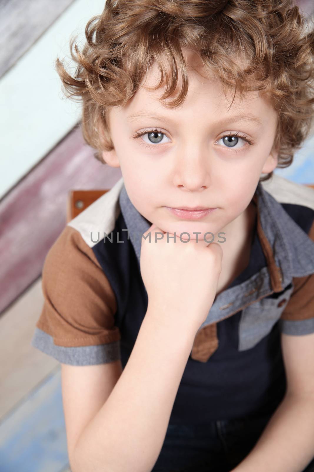 Young boy with curly blonde hair and blue shirt