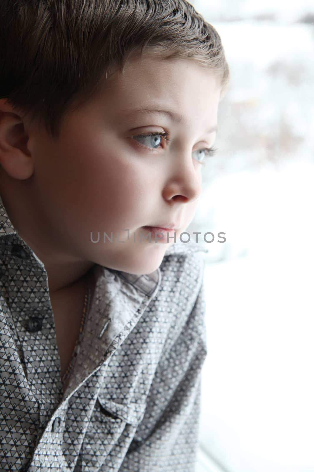 Young boy looking out of the window on a winters day
