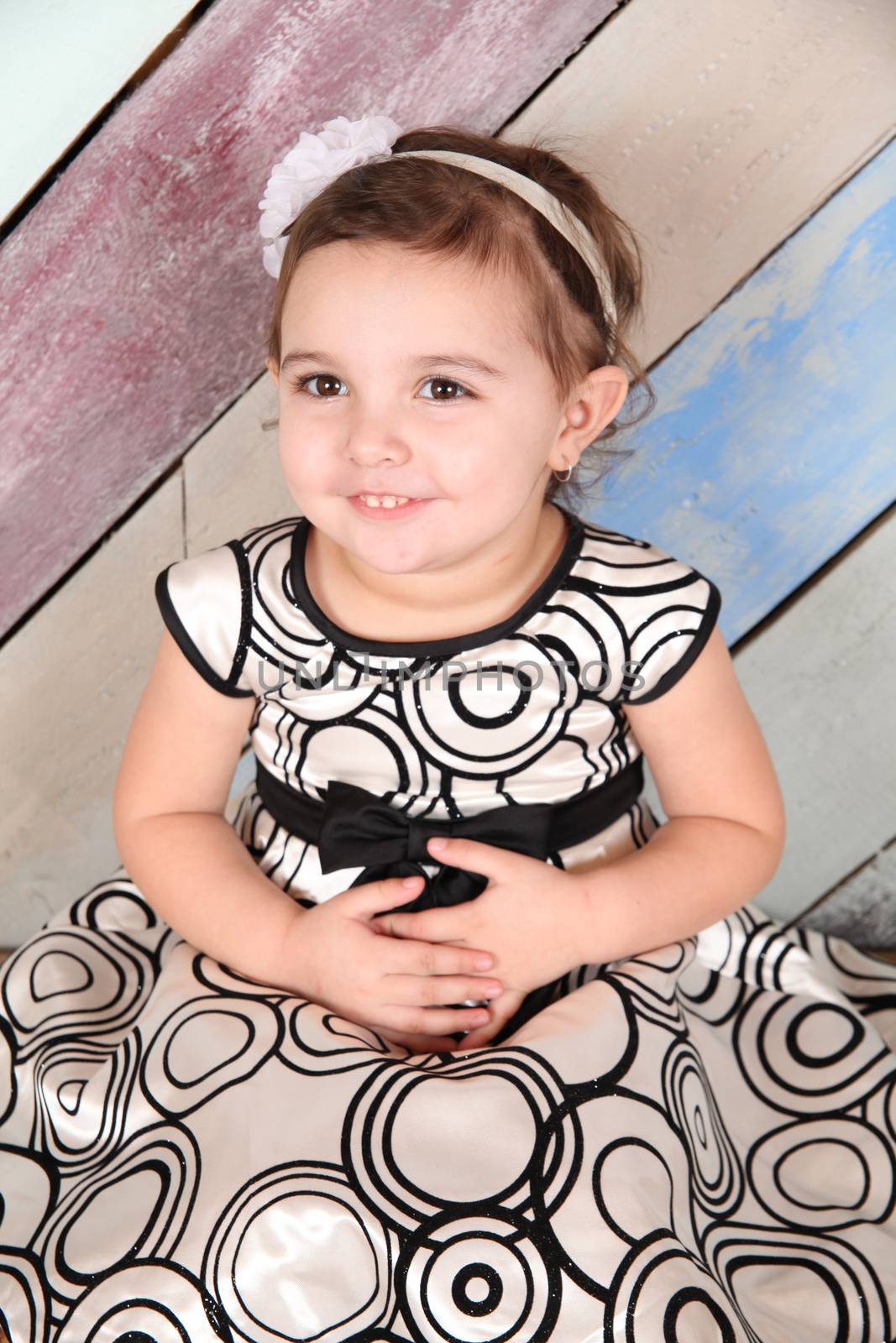 Brunette toddler girl against a colorful background