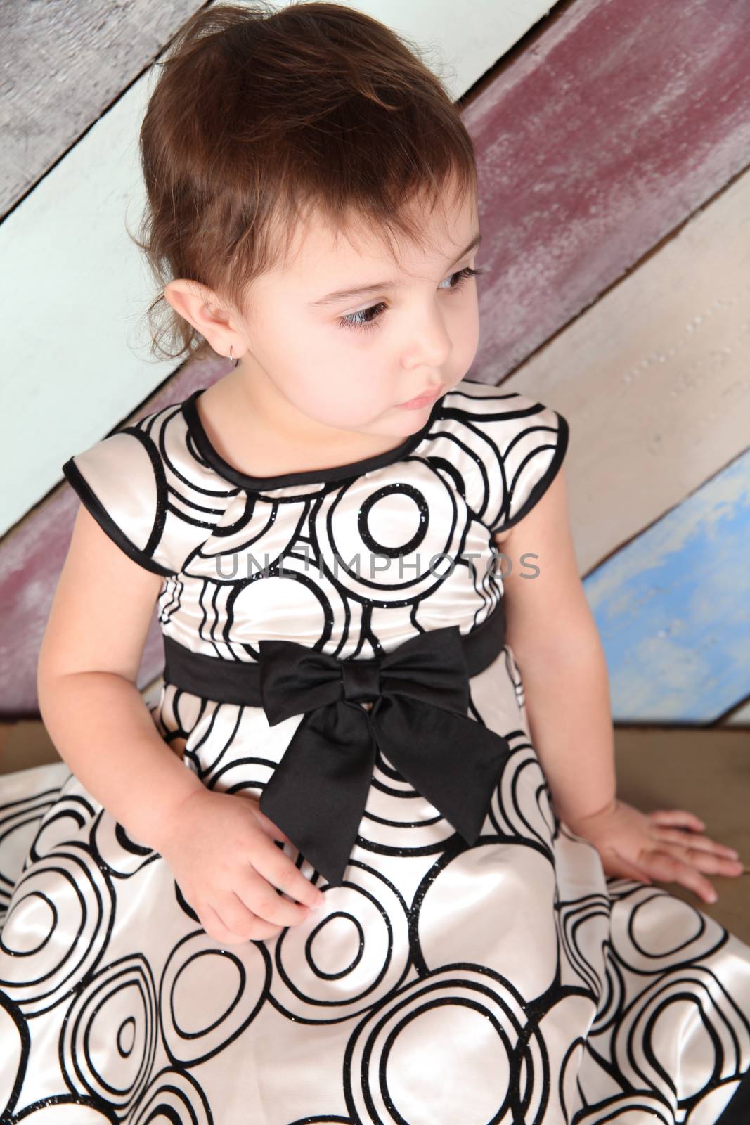 Beautiful brunette toddler girl against a striped background