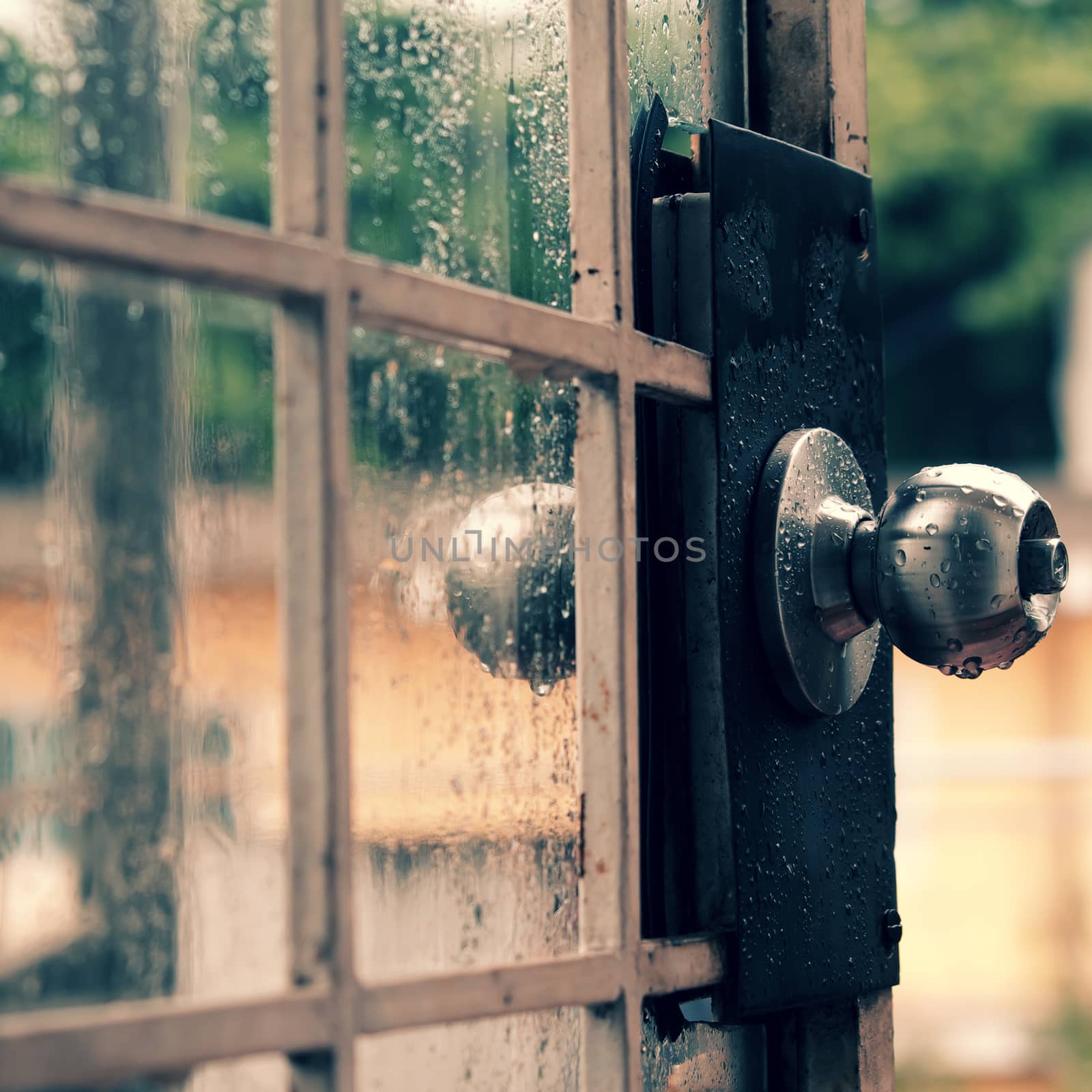 Rain drops on door handle and glass window in rainy day, drop of water falling make lonely feeling of cold day